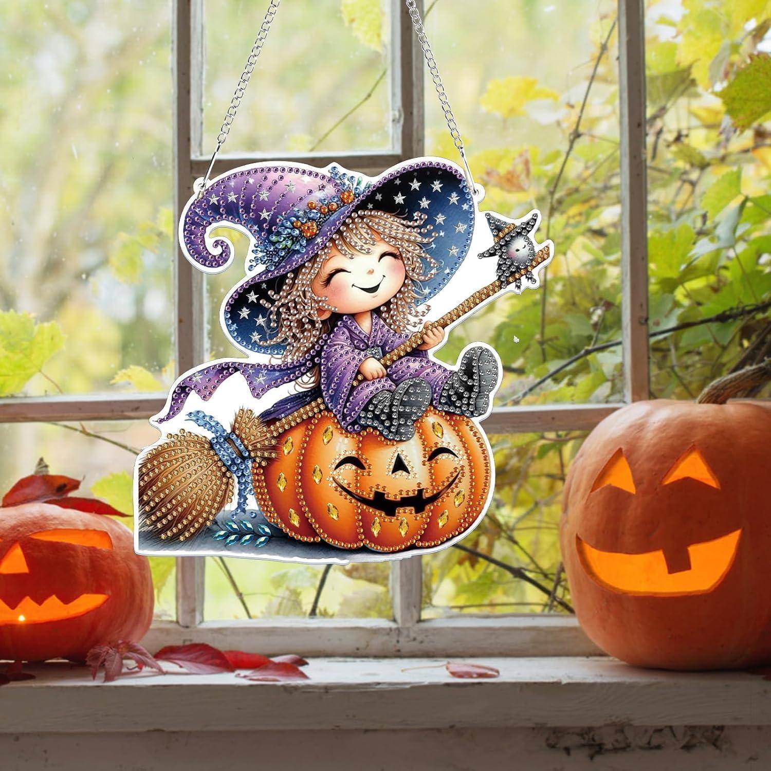 Eine lächelnde Hexendekoration sitzt auf einem geschnitzten Kürbis, der zwischen zwei leuchtenden Kürbissen auf einer Fensterbank zu Halloween hängt.