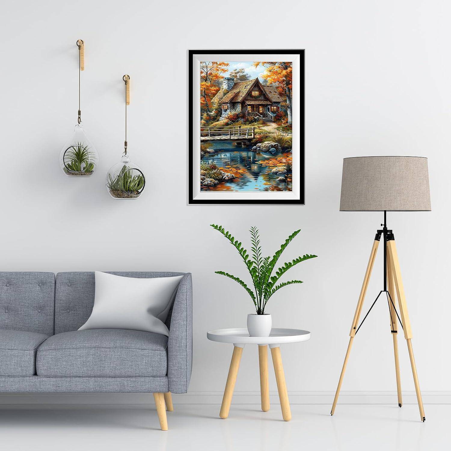 Modernes Wohnzimmer mit grauem Sofa, rundem Beistelltisch mit Pflanze, Stehleuchte mit Dreibein, Wandkunst und hängenden Blumenkübeln an einer weißen Wand.