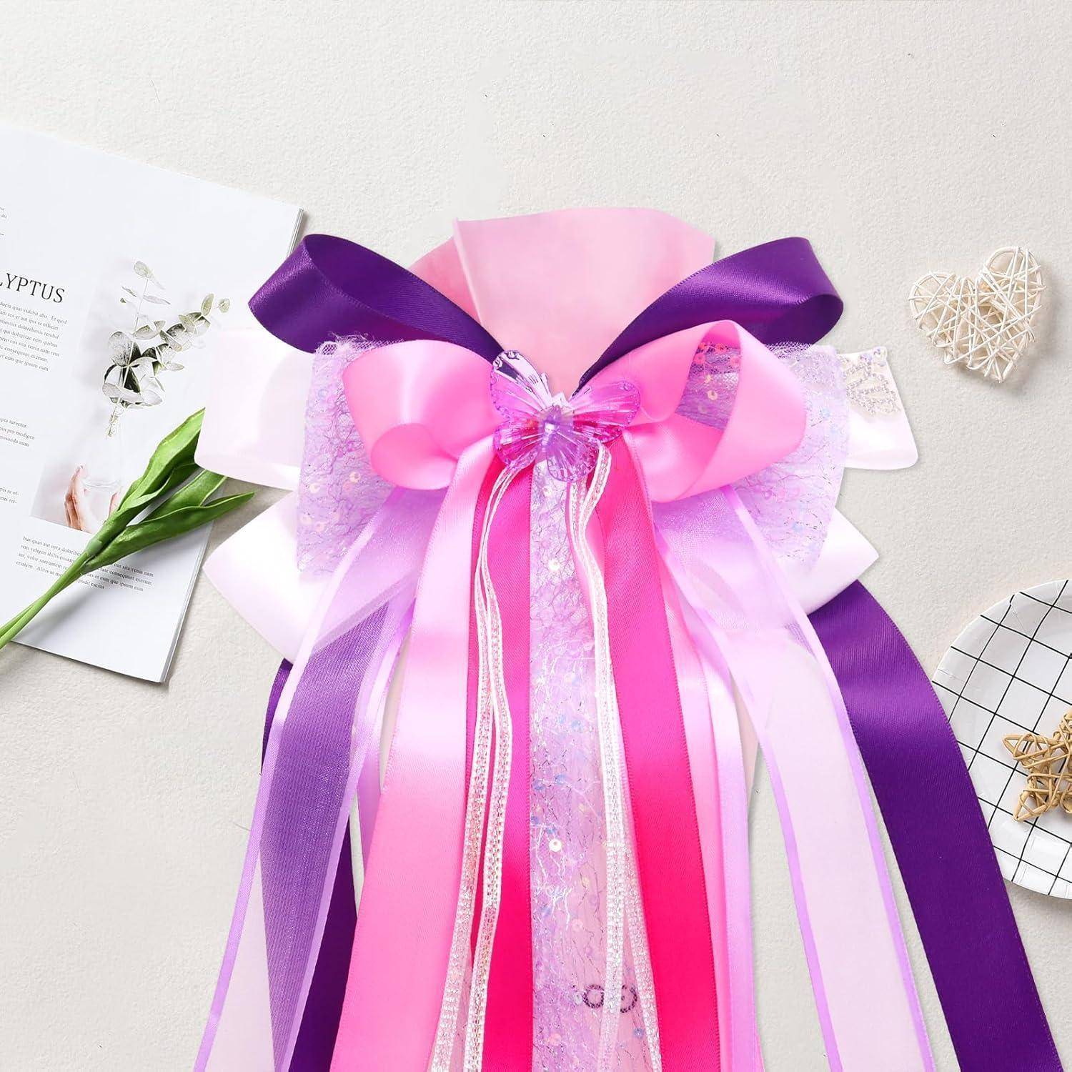 Rosa und violette dekorative Geschenkschleife mit mehrschichtigen durchsichtigen Bändern und einer zentralen Schleife, präsentiert auf einer hellen Oberfläche.