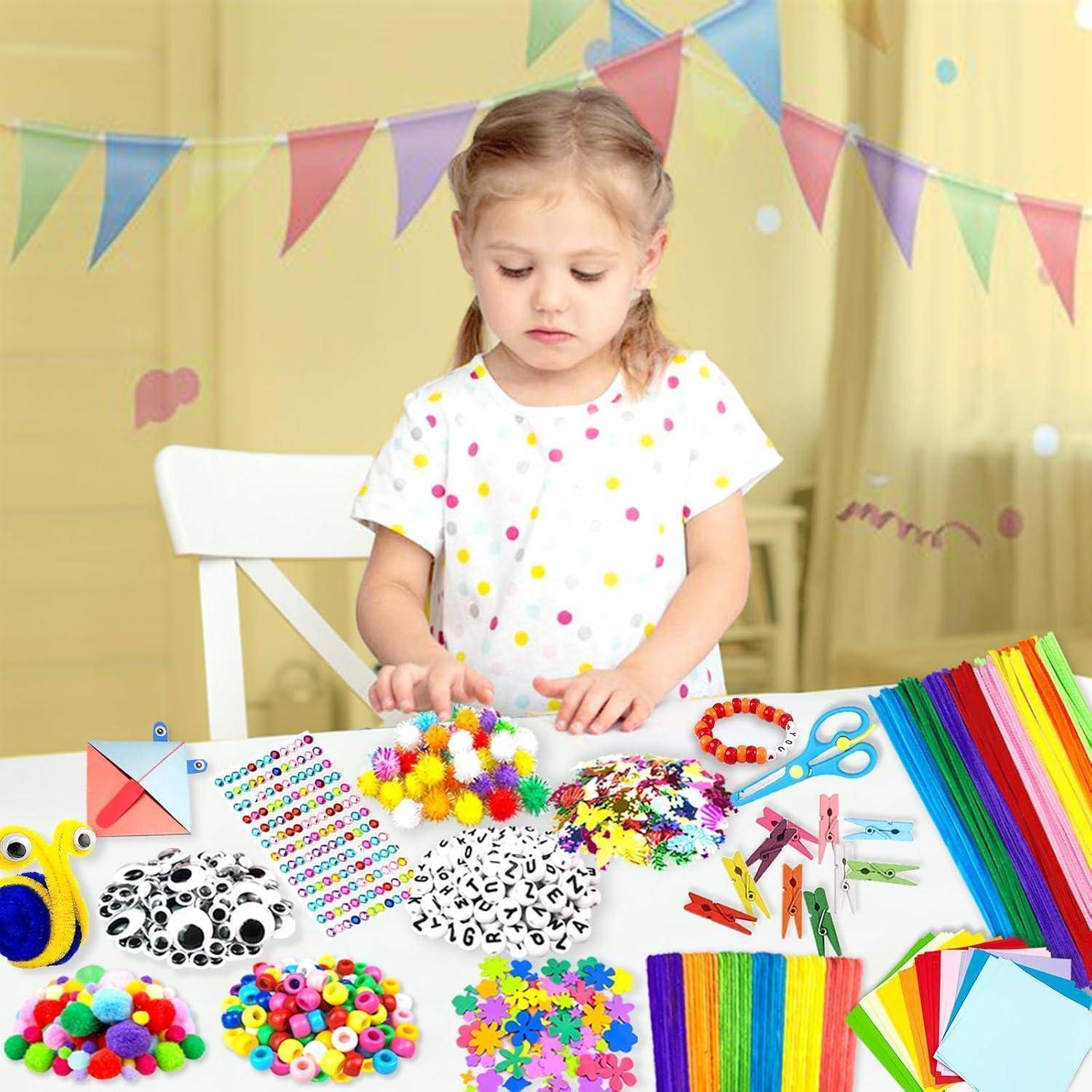 Junges Mädchen an einem Basteltisch, das bunte Pompons, Perlen, Aufkleber, Schere und Papierstreifen arrangiert, mit Wimpelketten-Dekorationen hinter ihr.