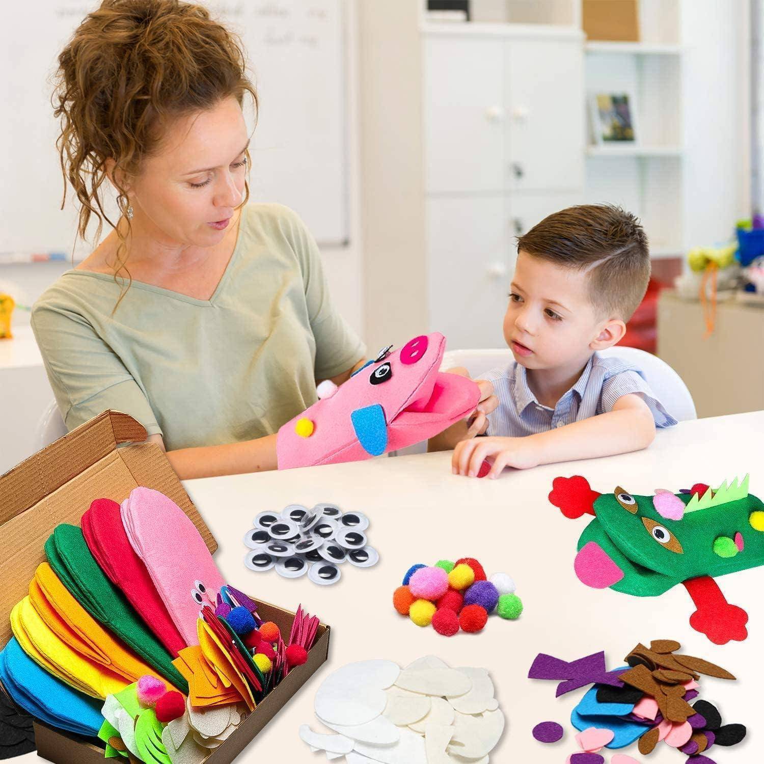 Frau und kleiner Junge basteln bunte Tierpuppenspieler an einem Tisch mit Papier, Wackelaugen, Pompon und ausgeschnittenen Teilen.