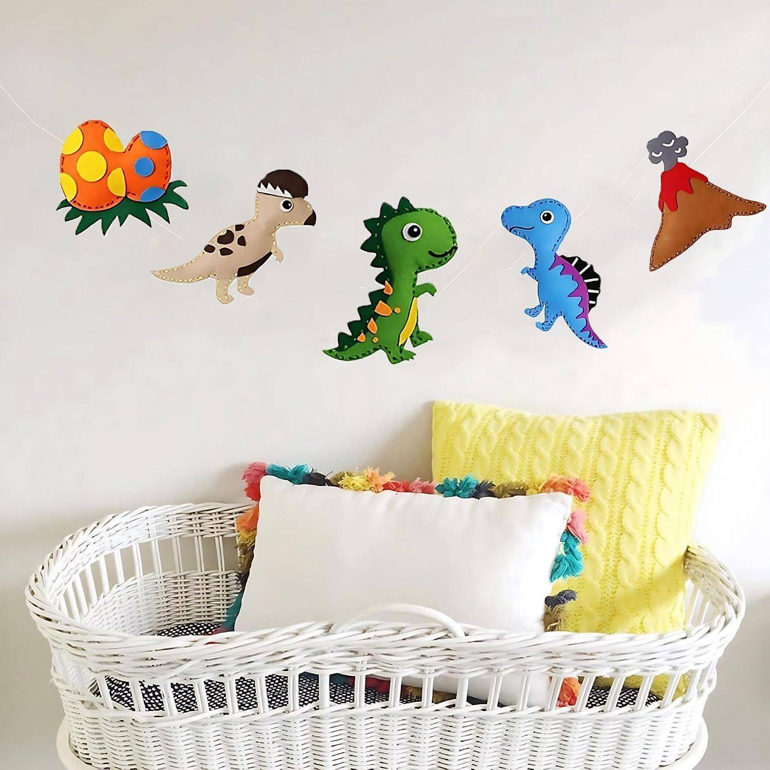Weißer Rattankorb mit Kissen unter bunten Filz-Dinosaurier- und Vulkan-Wanddekorationen