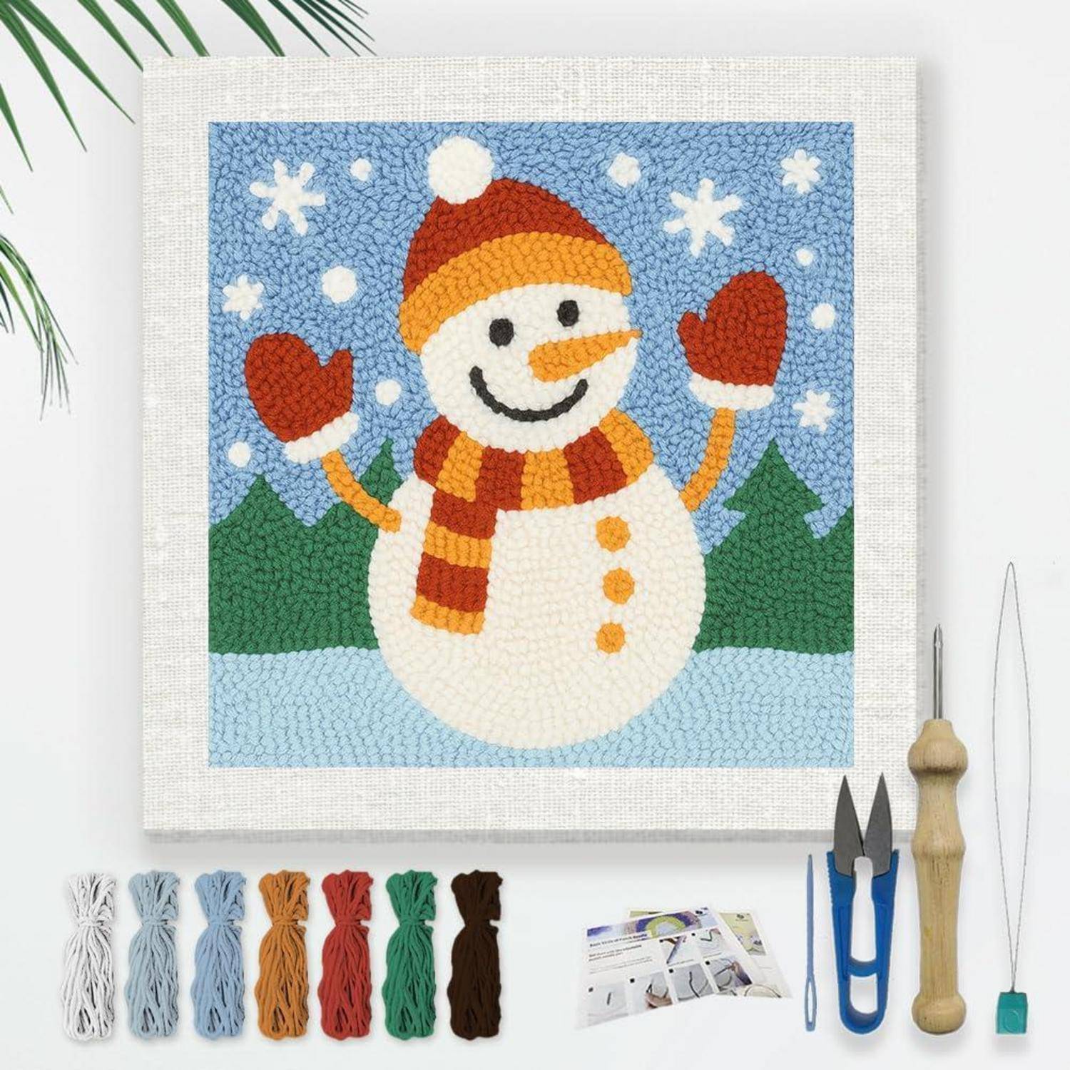 Bastelset mit fertiggestelltem Schneemann-Mosaik mit Garnbündeln, Werkzeugen und Anleitung zum Erstellen der Winterszene.