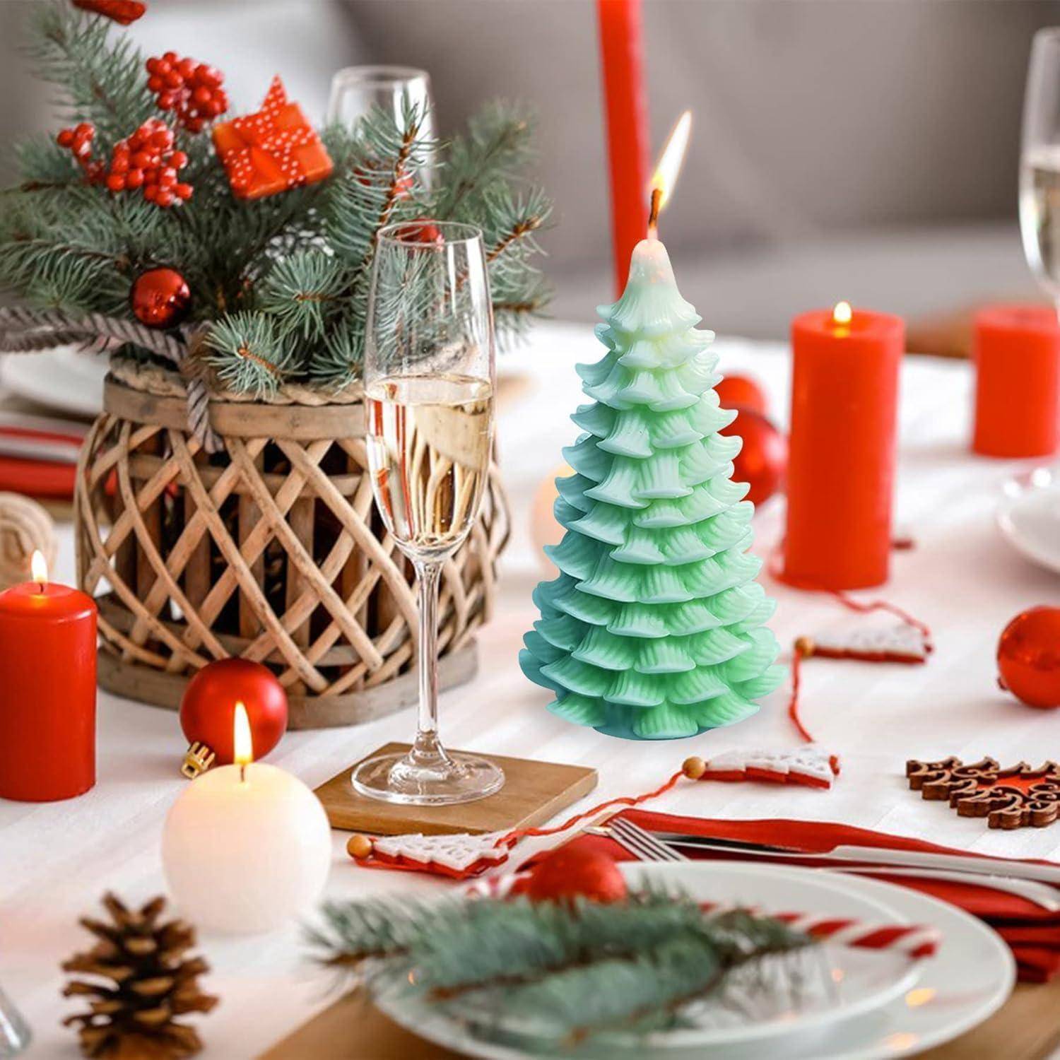Eine festliche Feiertagstischdeckung mit einer brennenden mintgrünen Weihnachtsbaumkerze, roten Kerzen, einem Champagnerglas, einer Tannenzapfen und einer Immergrün-Tischmitte.