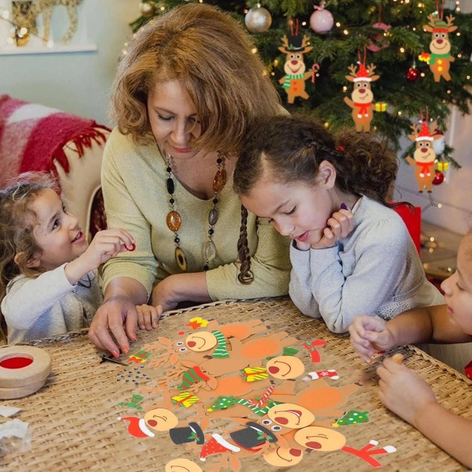 Eine Frau hilft drei Kindern, ein Rentier-Weihnachtsbastelprojekt an einem Tisch zu machen, der für Weihnachten dekoriert ist.