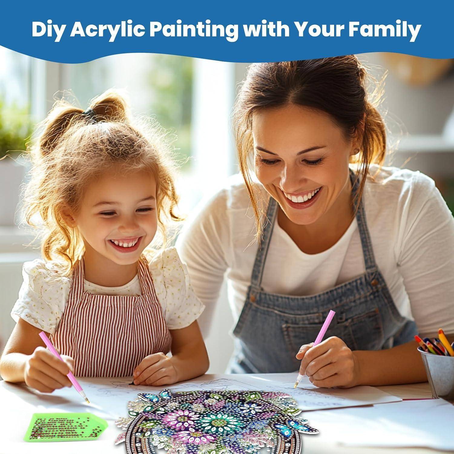 Mutter und kleine Tochter lächeln, während sie zusammen an einem Tisch Acrylmalerei betreiben, mit dem Titel „DIY-Acrylmalerei mit Ihrer Familie