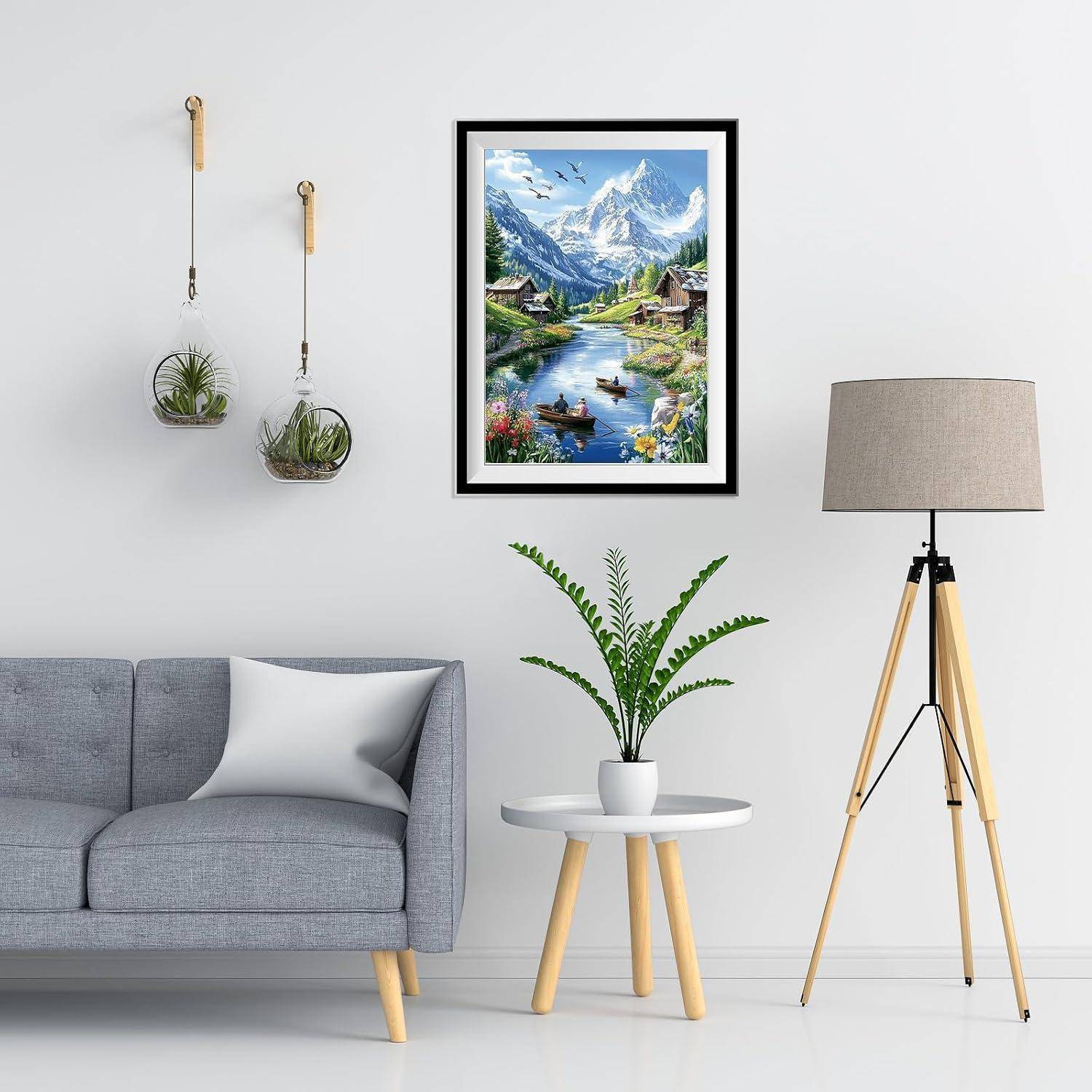 Modernes Wohnzimmer mit grauem Sofa, Beistelltisch und Pflanze, Stativ-Stehleuchte, Wandpflanzgefäße und einem gerahmten Berglandschaftsbild über dem Sofa.