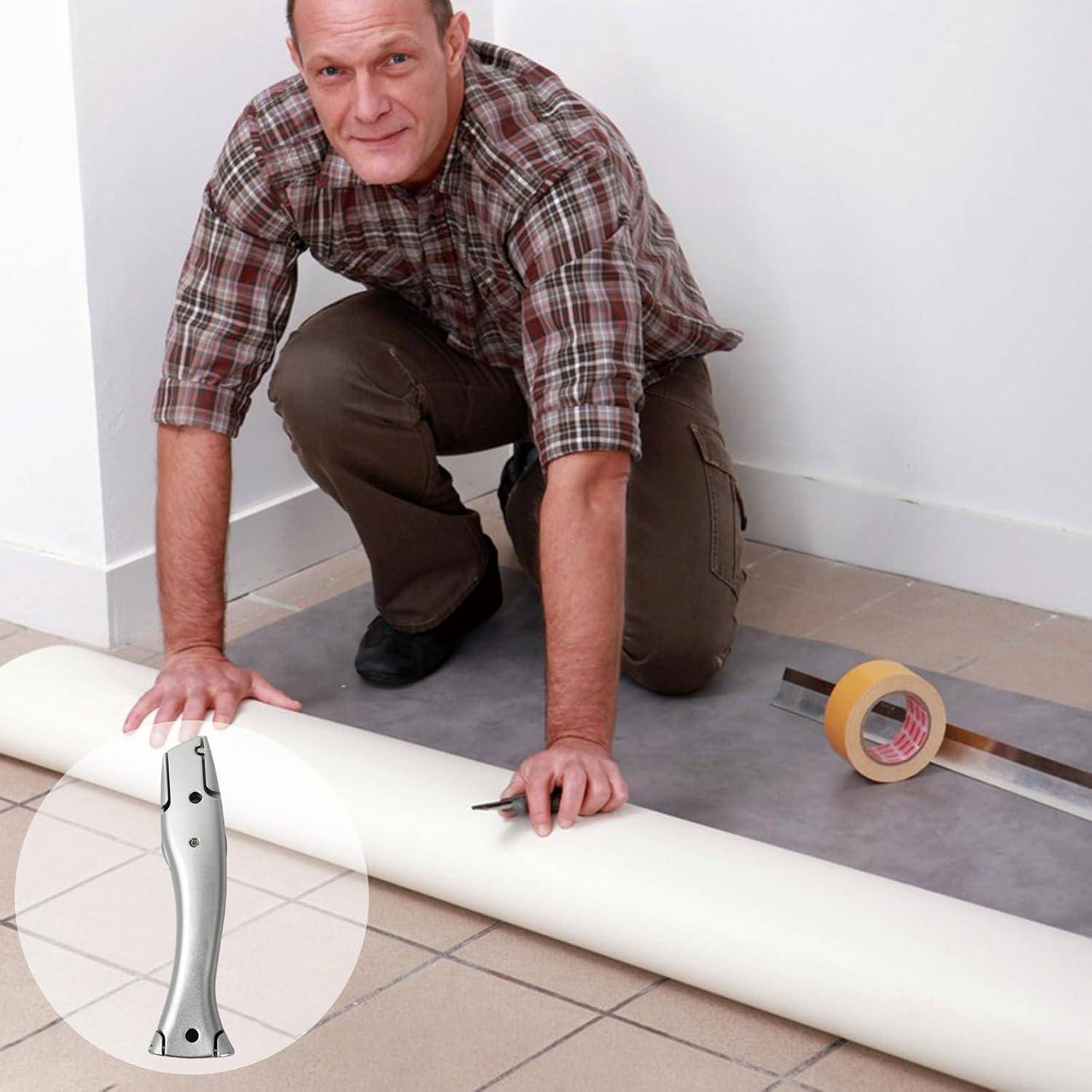 Ein Mann kniet auf einem Boden, misst und schneidet mit einem Messer eine weiße Bodenrolle, mit Klebeband in der Nähe.