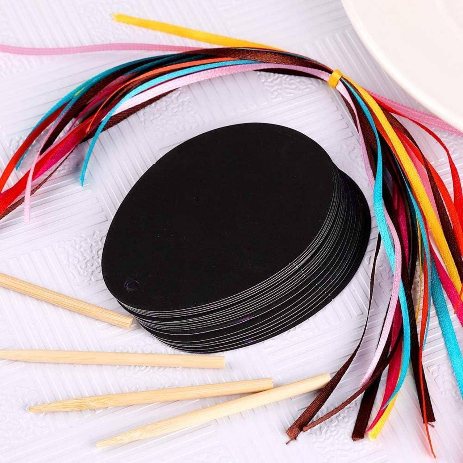 Schwarze ovale Papierstücke und bunte dünne Streifen zum Basteln oder Quilling, mit Holzstöckchen auf einer strukturierten weißen Oberfläche.