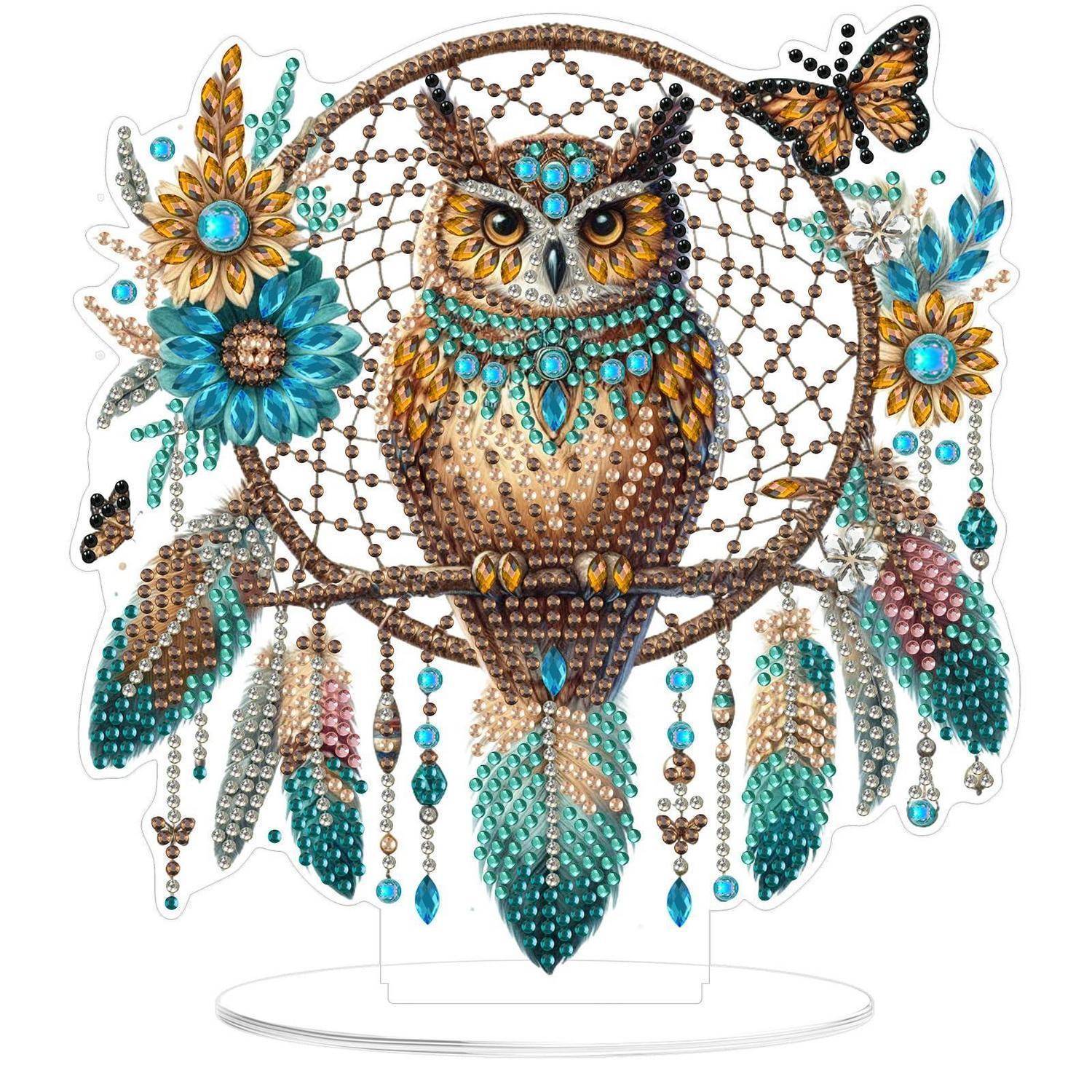 Verzierter Eulenschmuck mit Türkis- und Goldblumen, Schmetterlingen und baumelnden Perlenakzenten auf einem klaren Ständer zur Anzeige.