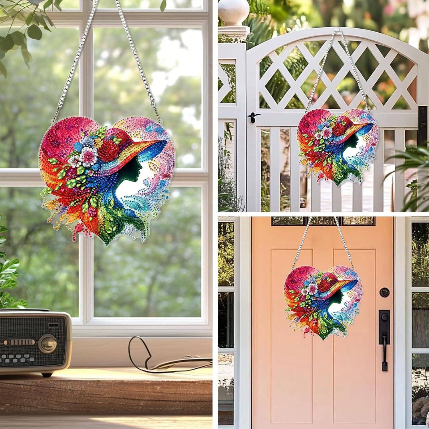 Bunte herzförmige Hängdekoration mit einem Fisch und Blumen, die drinnen an einem Fenster und draußen an einem Tor und einer Haustür ausgestellt ist.