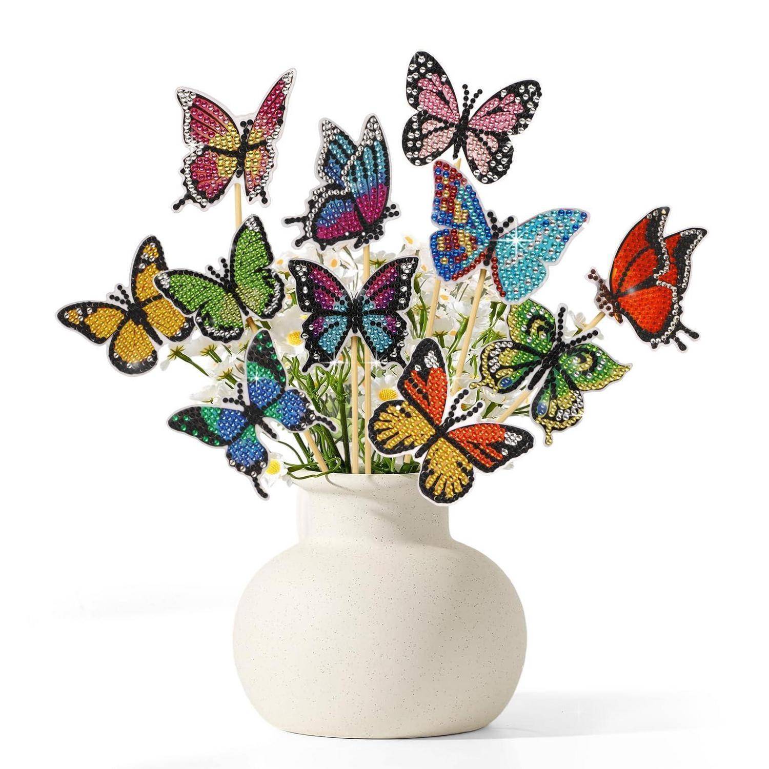 Dekorativer Blumenstrauß aus bunten Schmetterlingsornationen an Stielen in einer weißen Vase, wie Blumen arrangiert vor einem schlichten Hintergrund.