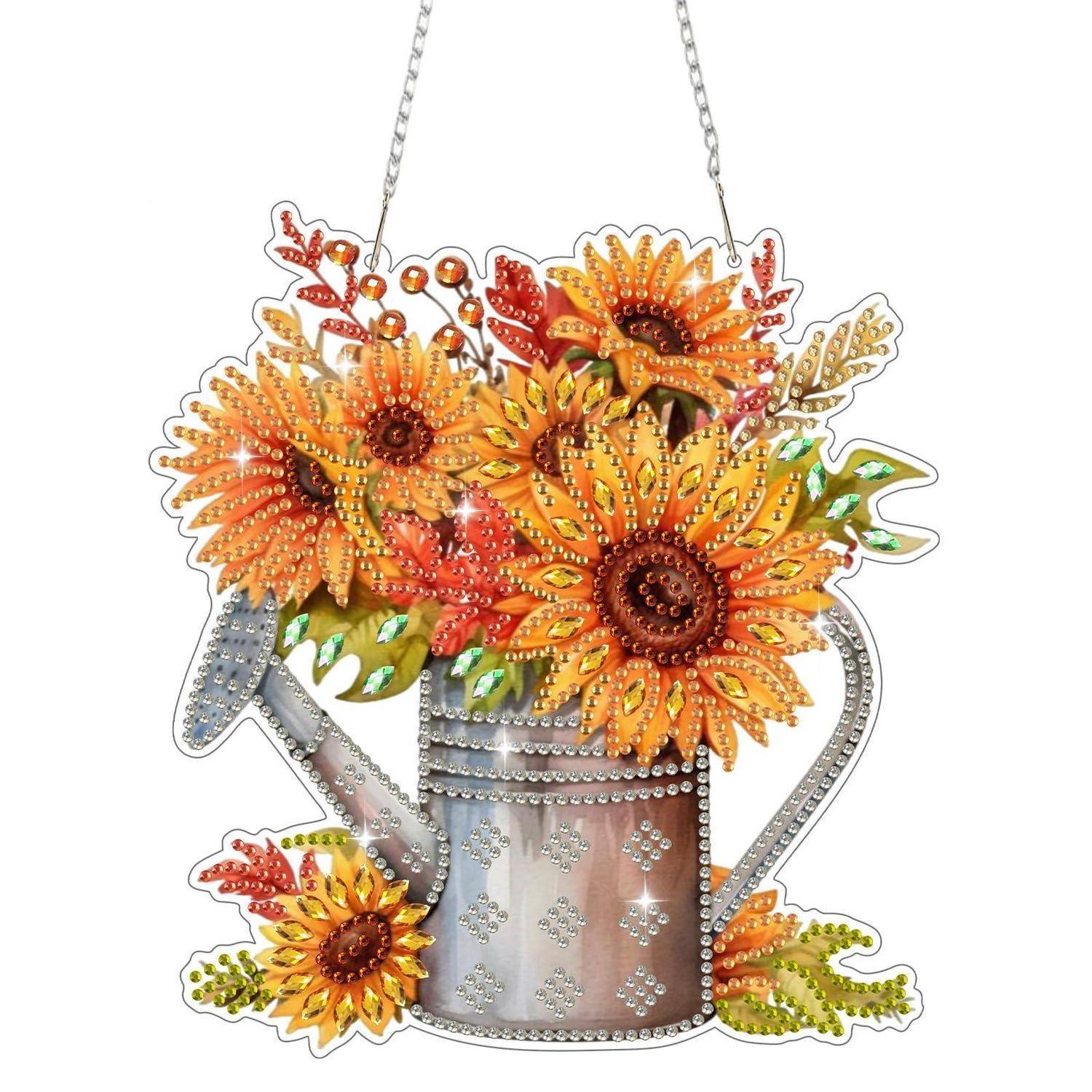 Dekorative Wanddekoration aus einer Metallgießkanne, die überläuft mit leuchtend orangefarbigen Sonnenblumen und Blättern, umrandet mit Strass und einer Aufhängekette.