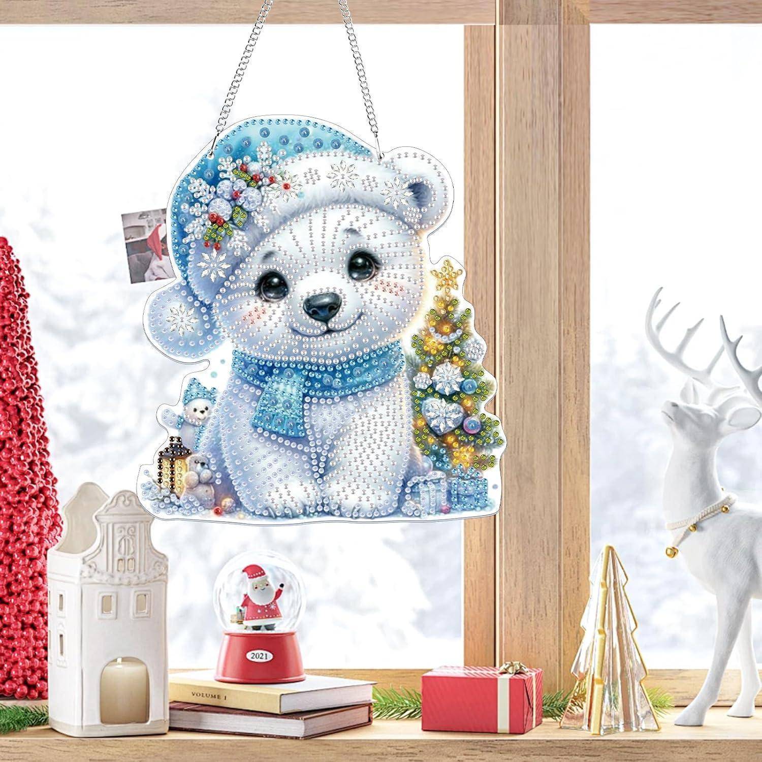 Winterliche Schaufenstergestaltung mit einem hängenden, mit Juwelen besetzten Bärenanhänger, der einen blauen Hut und einen Schal trägt, neben einem leuchtenden Baum, einer Geschenkbox und einer dekorativen Hirschfigur.