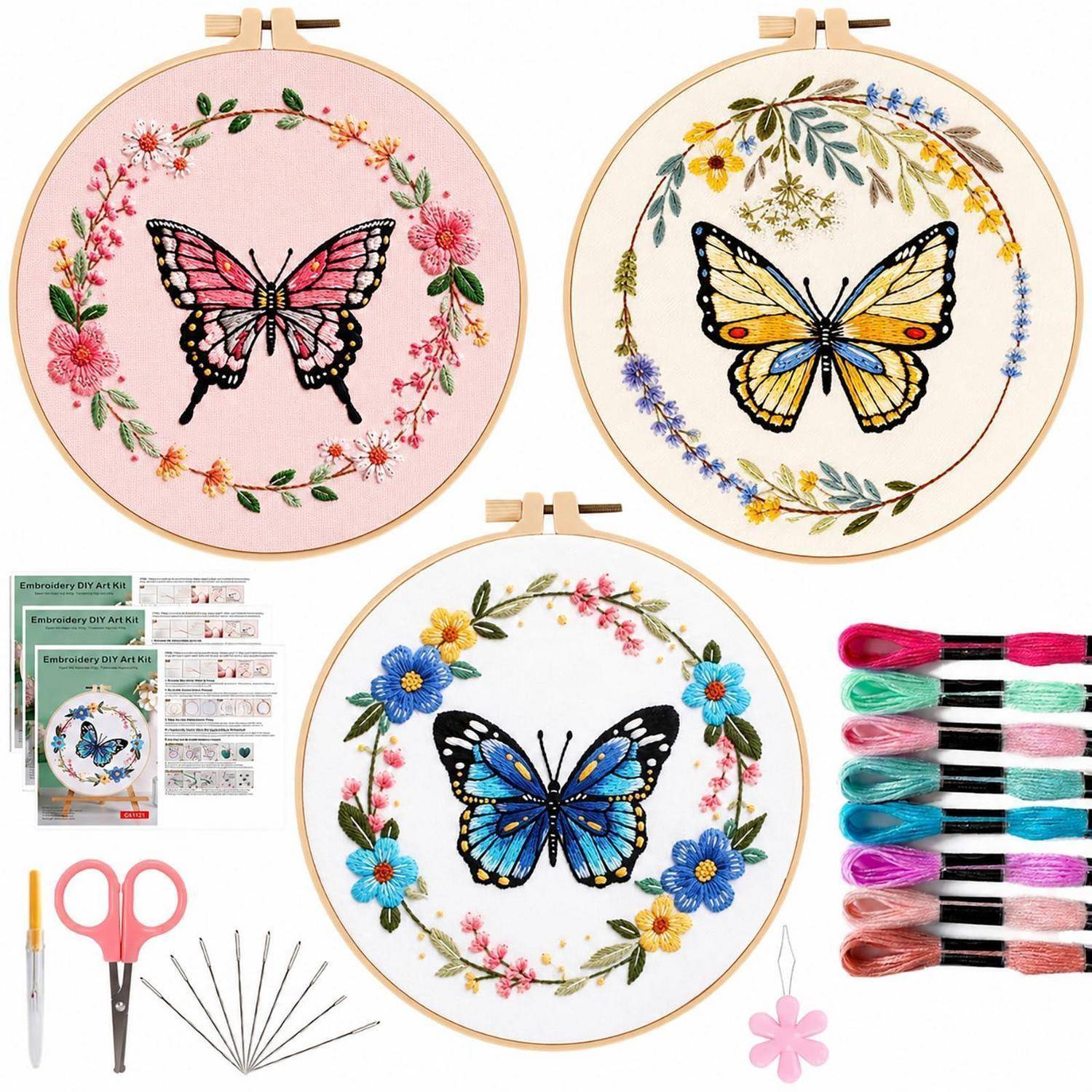 Stickerei-Set-Bild mit drei fertigen Reifen-Designs mit Schmetterlingen und Blumenkränzen, plus Nadeln, Schere, Faden und Musteranleitungen.