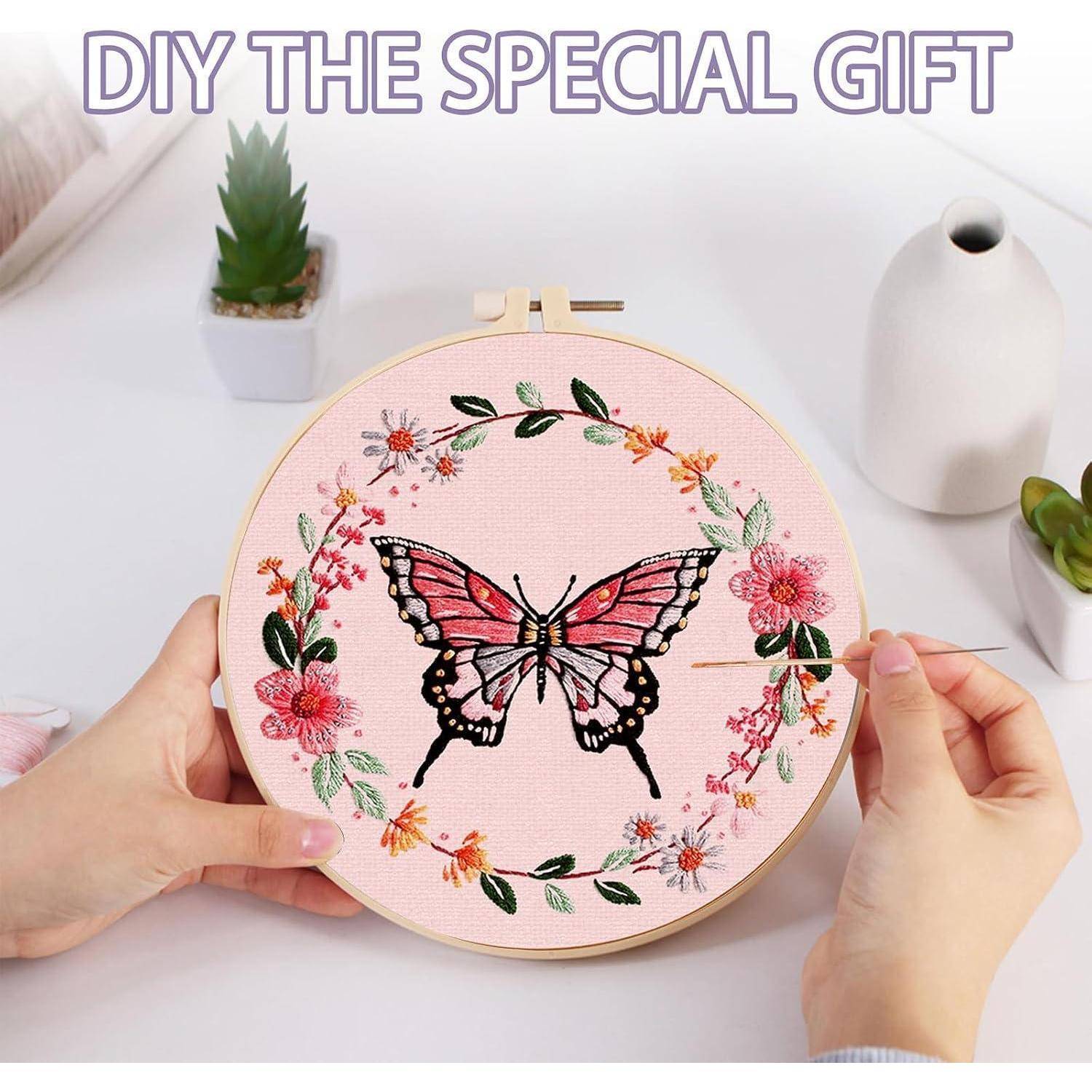 Hände besticken einen rosa Reifen mit einem Schmetterling und einem Blumenkranz, mit dem Text 
