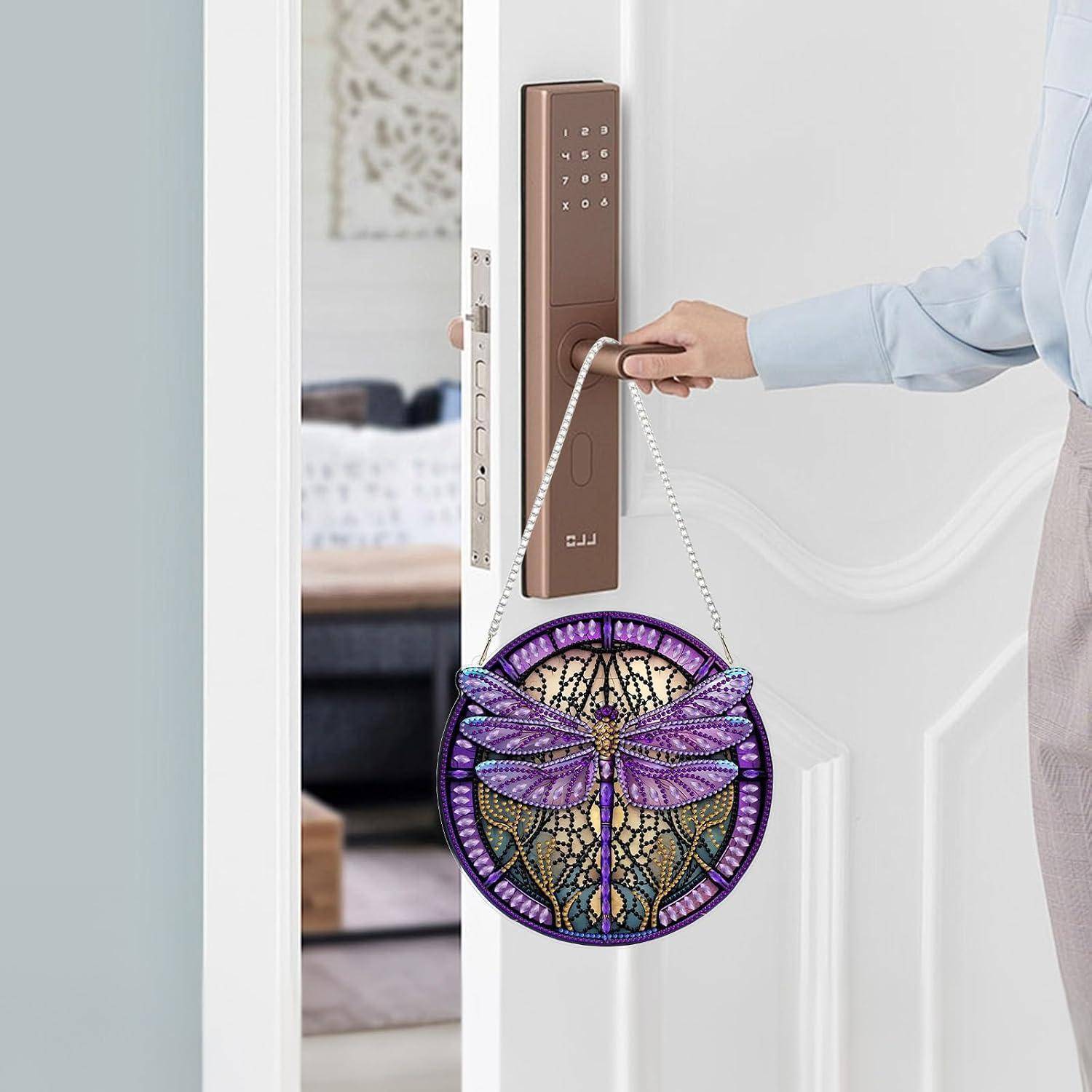 Eine Person benutzt ein braunes smartes Türschloss, um eine weiße Tür zu öffnen; ein rundes violettes Schmetterlingsdesign hängt am Griff.