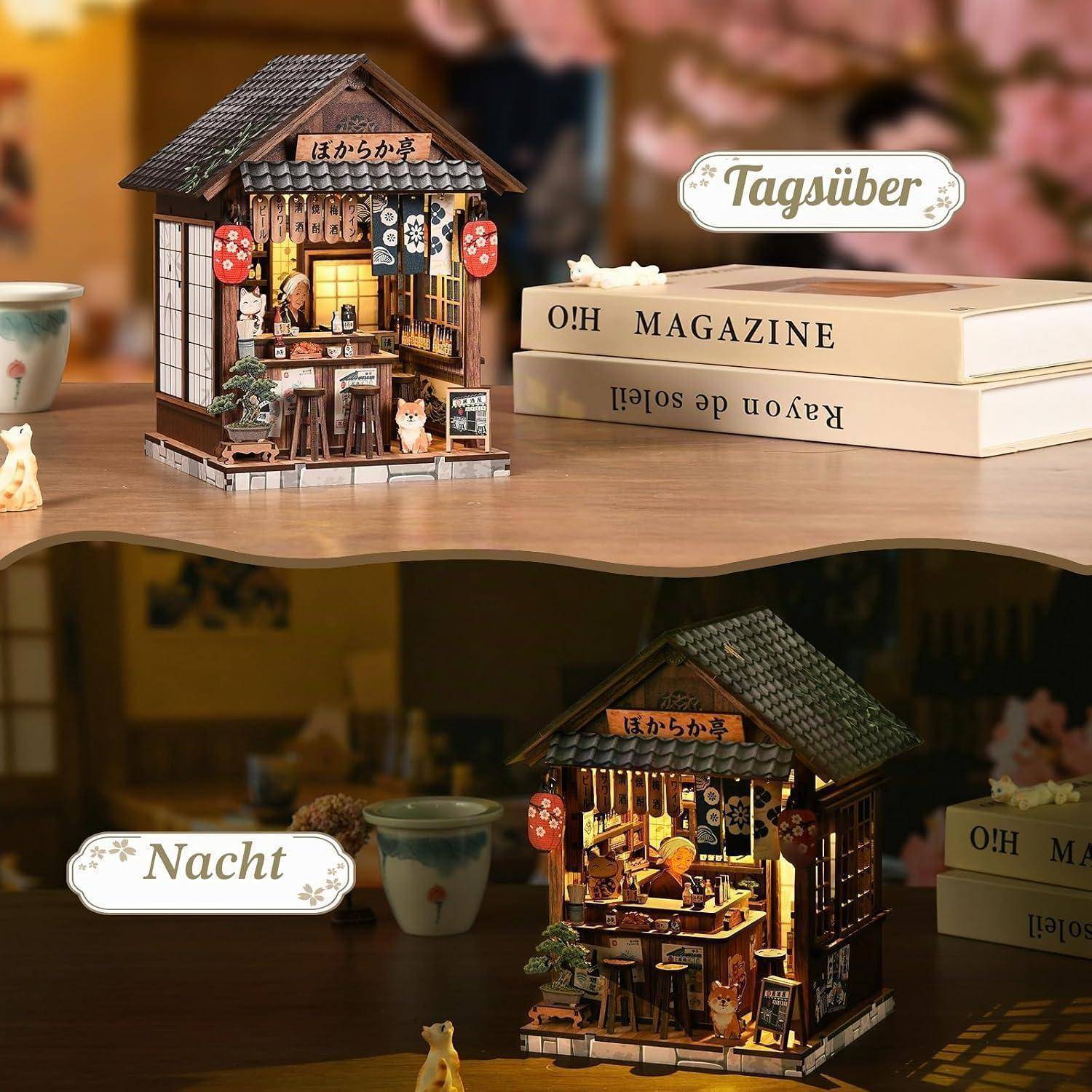 Miniatur-Japanisches Geschäftsdisplay auf einem Tisch, am Tage gezeigt und nachts beleuchtet, mit Laternen, Büchern und kleinen Figuren.
