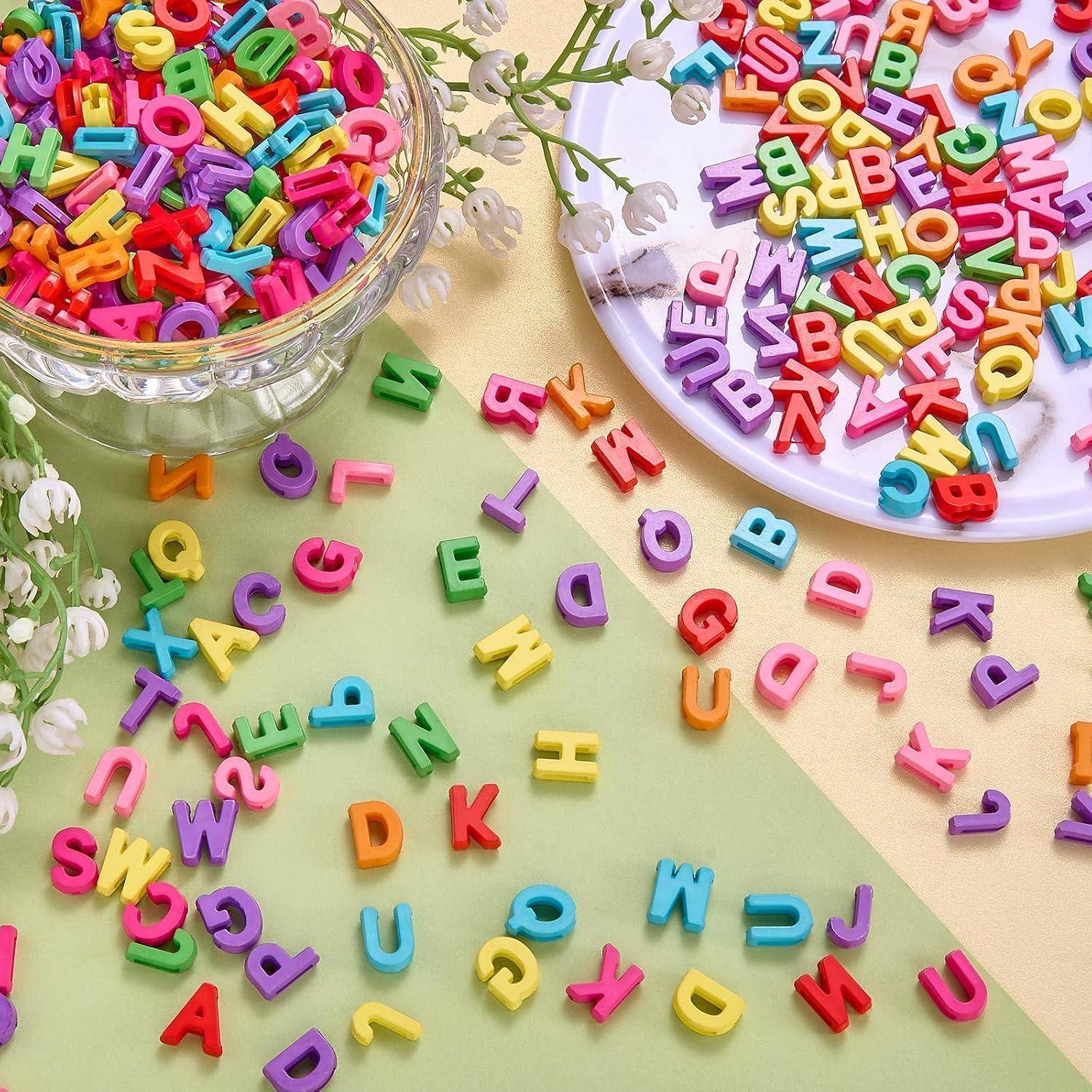 Bunte Kunststoff-Buchstaben verstreut auf einer Pastelloberfläche, mit weiteren Buchstaben in Schüsseln und auf einem Teller, was auf Lernen oder kreatives Spielen für Kinder hindeutet.