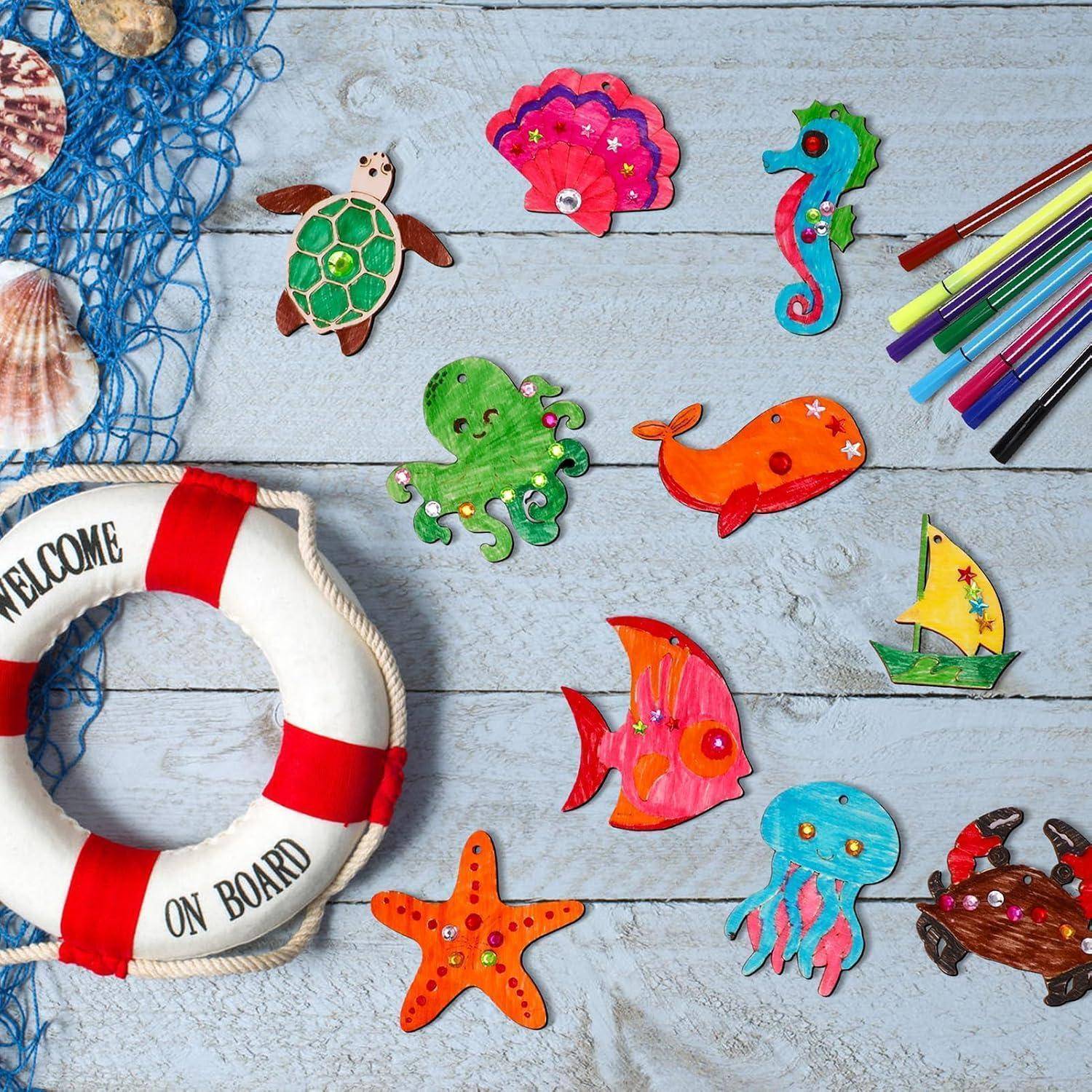 Bunte, handgefertigte Meereslebewesen- und Muschelhandwerk auf einer verwitterten blauen Holzoberfläche, mit einem Rettungsring mit der Aufschrift "WILLKOMMEN AN BORD"".