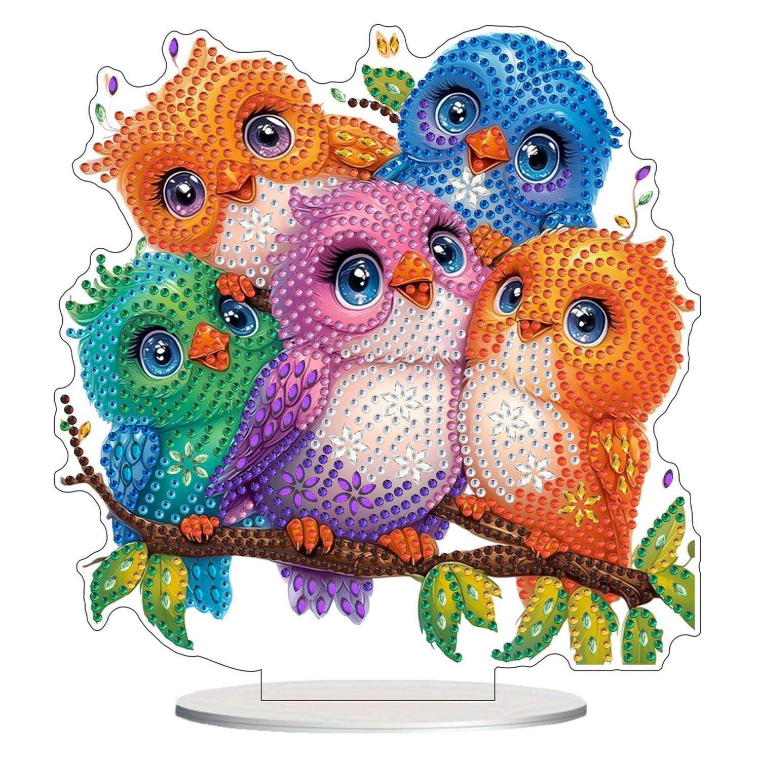Fünf bunte, mit Juwelen besetzte Cartoon-Vögel, die zusammen auf einem Ast sitzen, dargestellt als dekoratives Standbildstück.