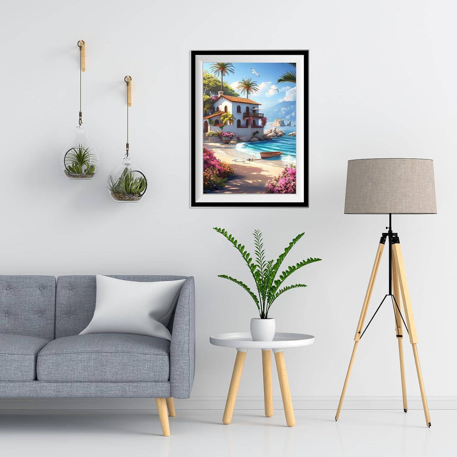 Modernes Wohnzimmer mit grauem Sofa, gerahmtem Gemälde eines tropischen Strands, hängenden Pflanzen, einer kleinen Pflanze auf einem runden Tisch und einer Stehleuchte auf Dreibeinen.