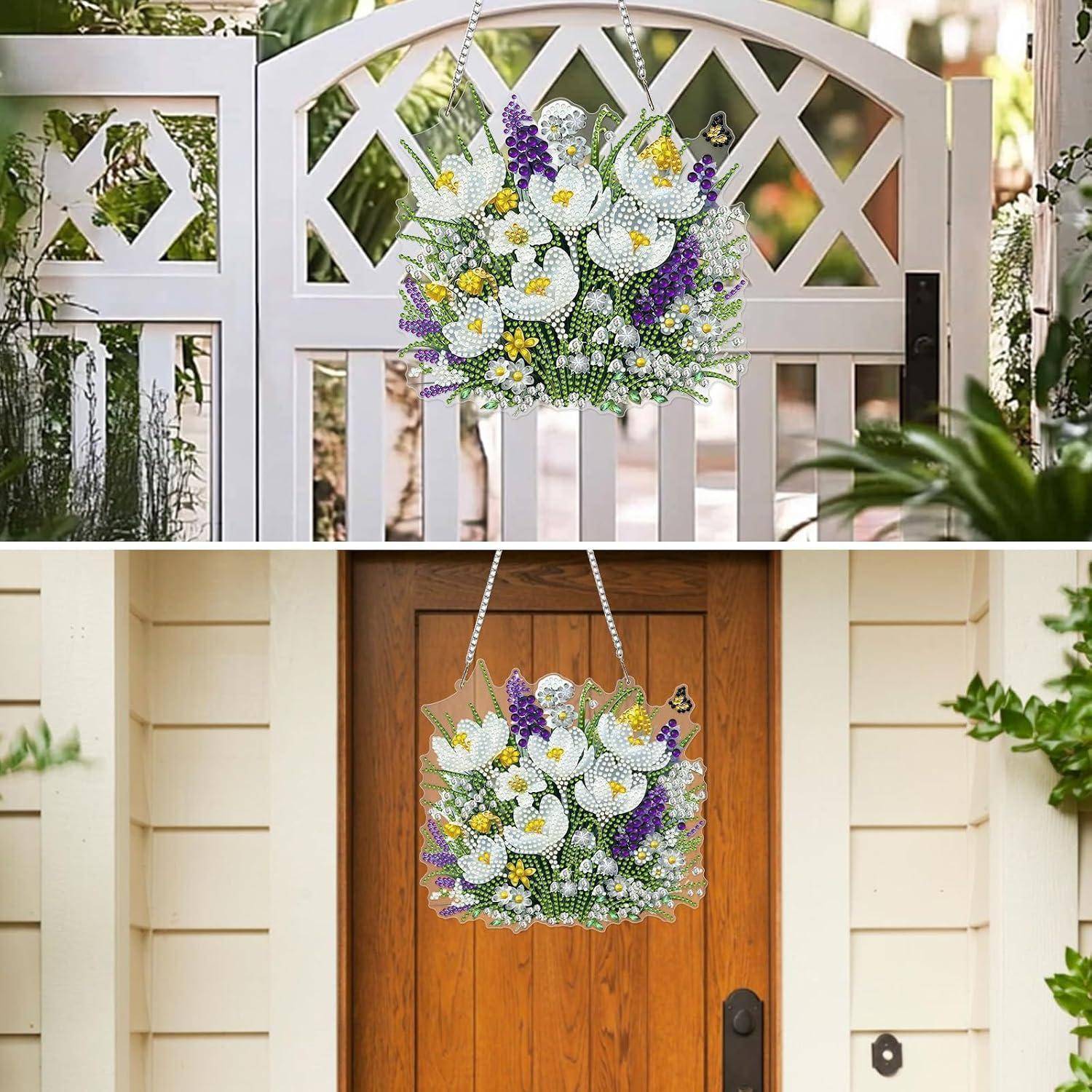 Ein hängendes Blumenschild mit weißen Calla-Lilien, Gänseblümchen und violetten Blumen, das an einem Tor und einer Haustür angebracht ist und auf eine dekorative Eingangsbereichgestaltung hindeutet.
