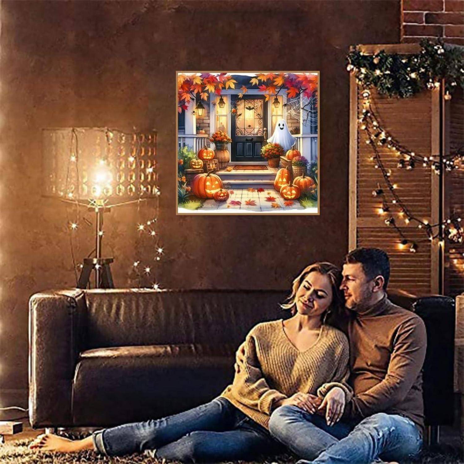 Ein Paar sitzt auf einem Sofa in einem gemütlich eingerichteten Zimmer, mit einer leuchtenden Herbst-/Halloween-Veranda-Szene, die an der Wand hinter ihnen angezeigt wird.