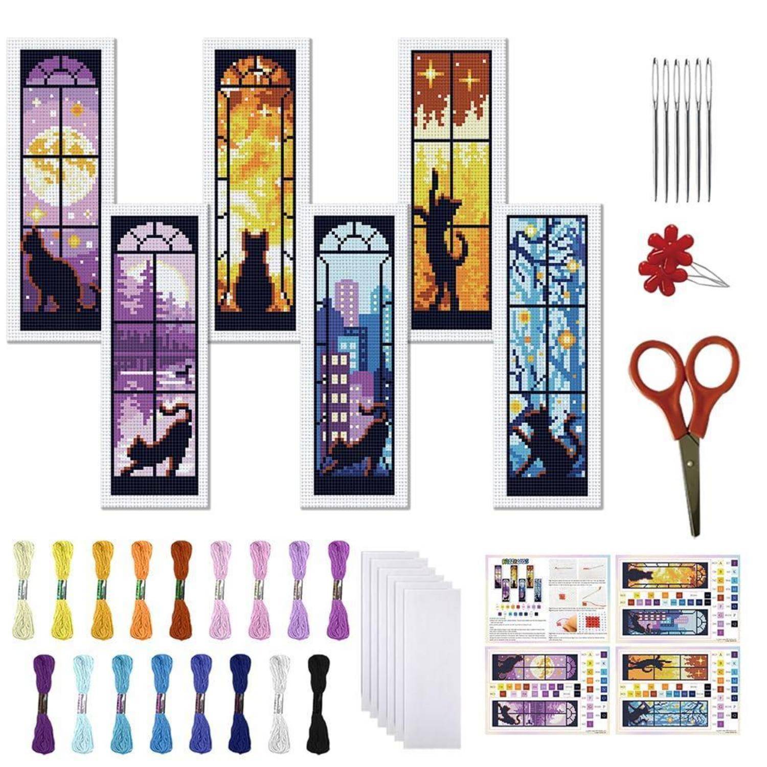 Cross-Stitch-Set mit Bild, das sechs bunte Fenster-Lesezeichen mit Katzen im Buntglasstil, Stickgarn, Nadeln, Schere, Faden und Anleitungsblätter zeigt.