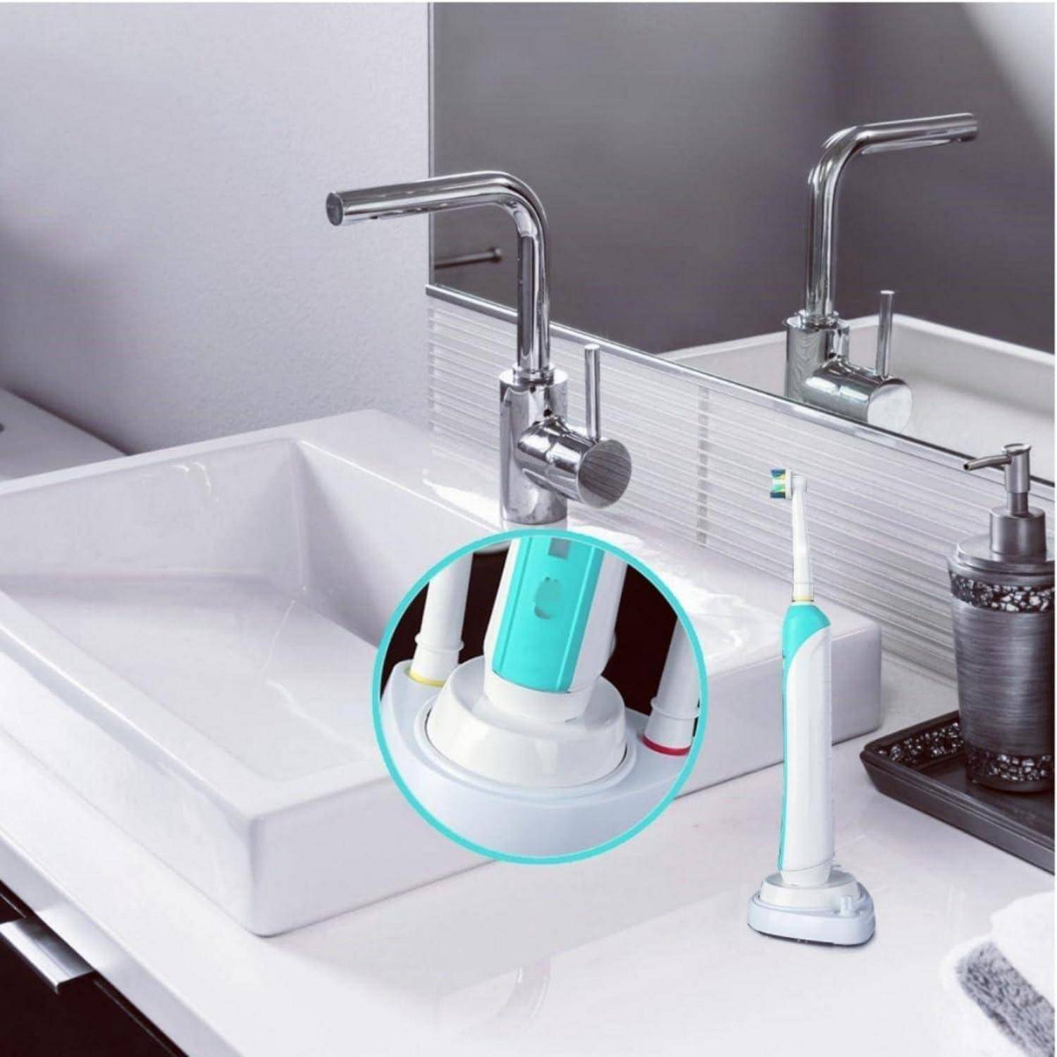 Elektrische Zahnbürste, die auf einem Badezimmerwaschtisch neben einem Wasserhahn steht, mit einer eingefügten Nahaufnahme ihrer Ladestation und Bürstenköpfe.