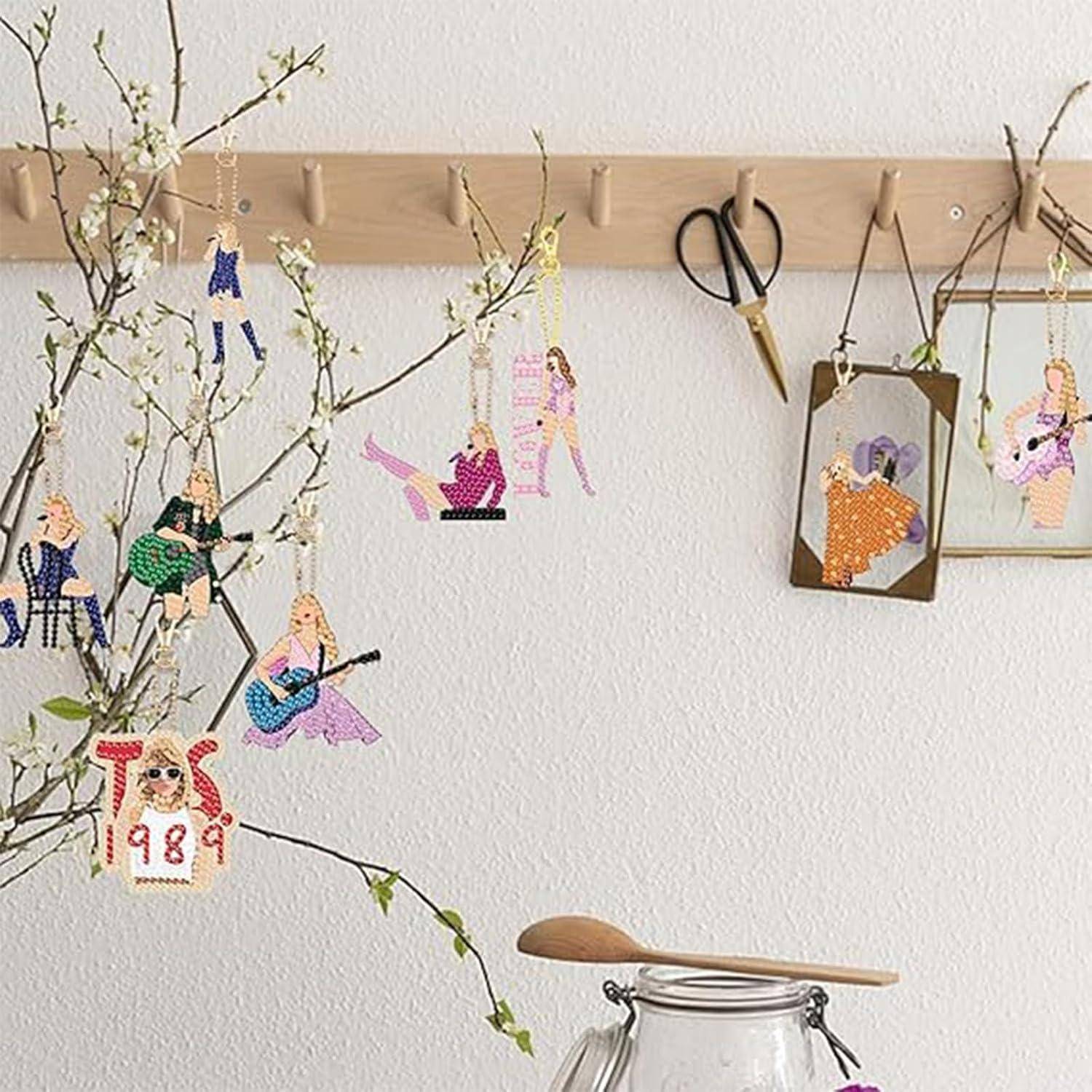 Kreuzstich-Ornamente von Musikern und Figuren, die an einem Wandastdisplay hängen, mit Scheren und gerahmten Nadelarbeiten auf einem hölzernen Pflockregal.