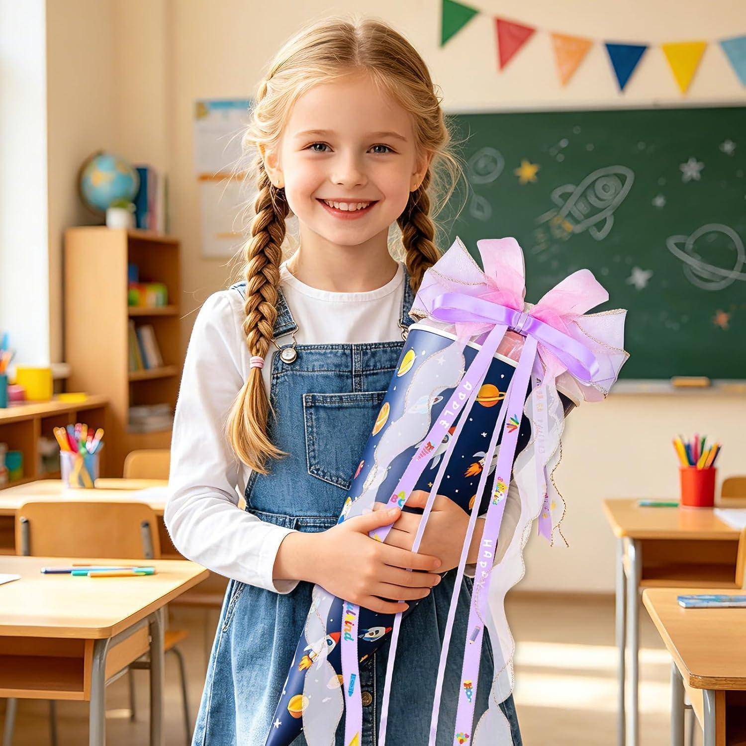 Lächelndes junges Mädchen in einem Klassenzimmer, das ein verpacktes Geschenk mit einer rosa Schleife hält und vor einer Tafel steht.