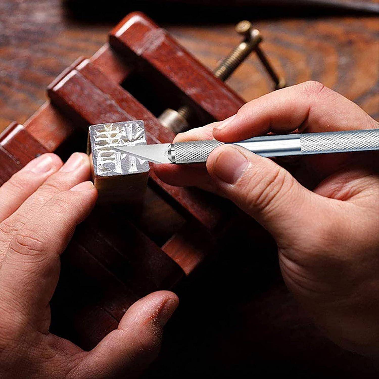 Hände, die einen kleinen Block mit einem Universalmesser bearbeiten, während dieser in einem Holzschraubstock eingespannt ist, zeigen detaillierte Holzblock- oder Stempelherstellung.