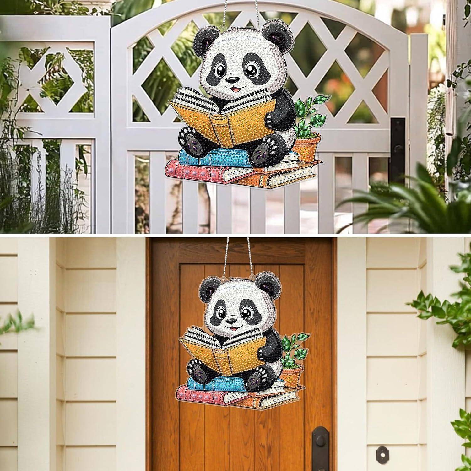 Ein dekoratives Panda, das ein Buch liest, dargestellt als ein Hängeschild an einem weißen Tor und einer hölzernen Haustür.