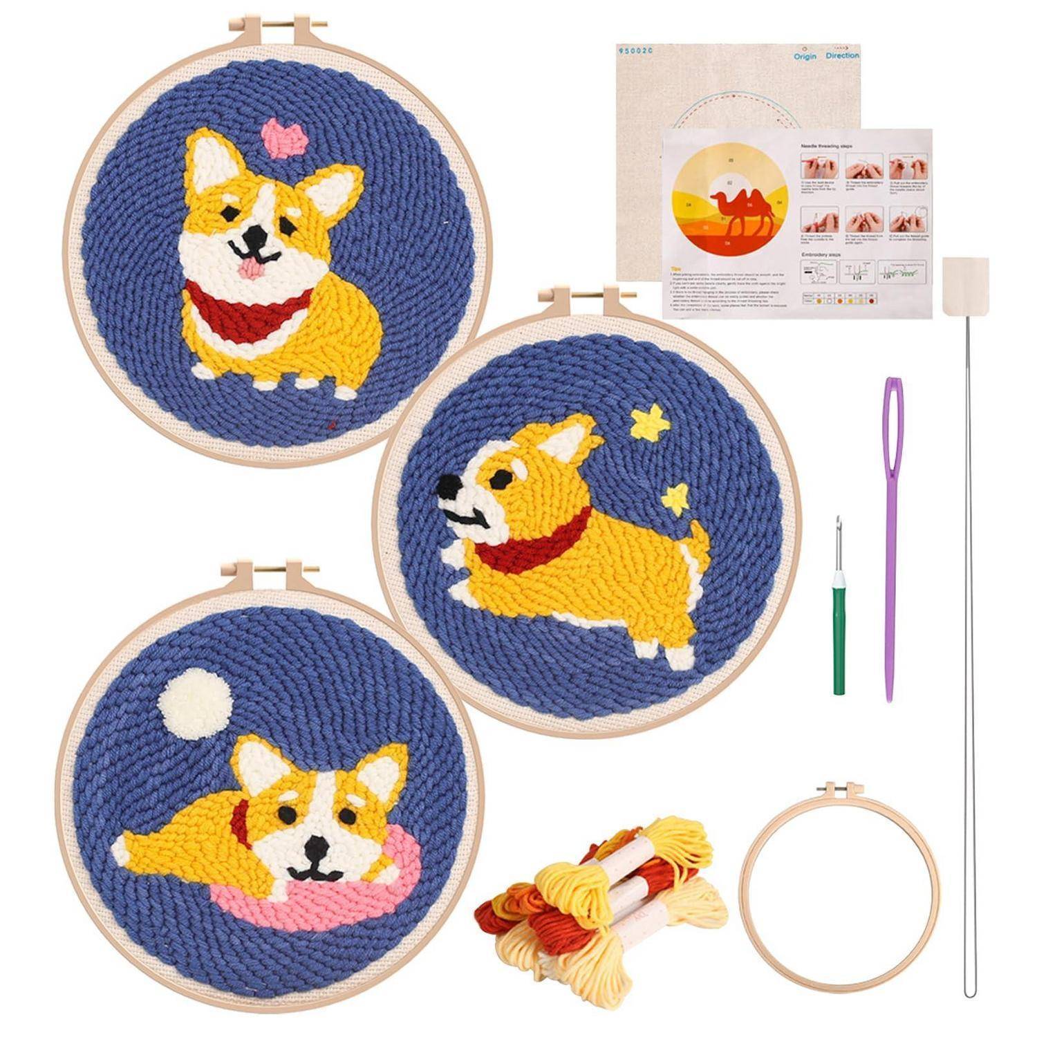 Stickset-Bild mit drei runden Reifen-Designs eines Corgi-Hundes mit Garn, Werkzeugen und beigefügtem Anleitung­sblatt.