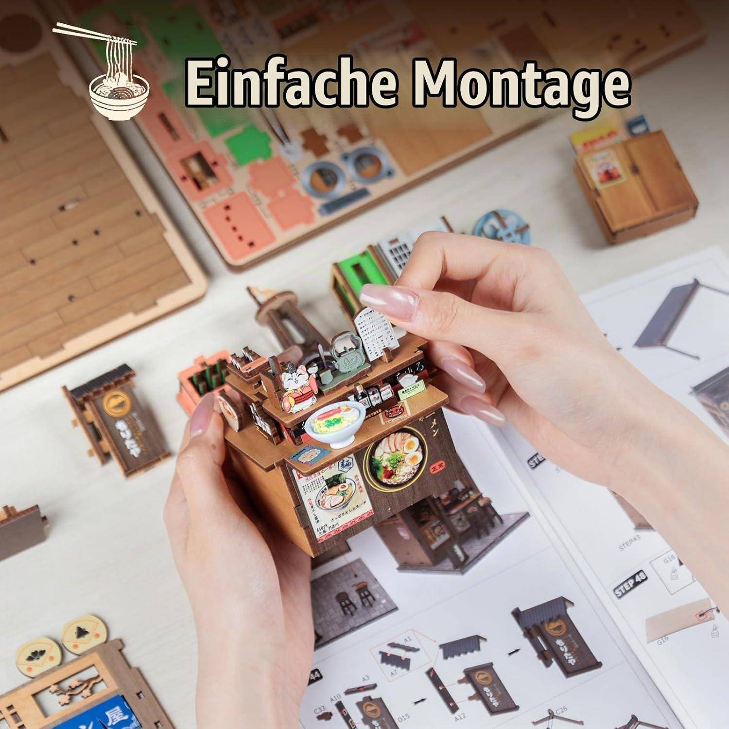 Hände, die ein Miniaturmodellhaus über einem Anweisungsblatt zusammenbauen, mit dem Text 