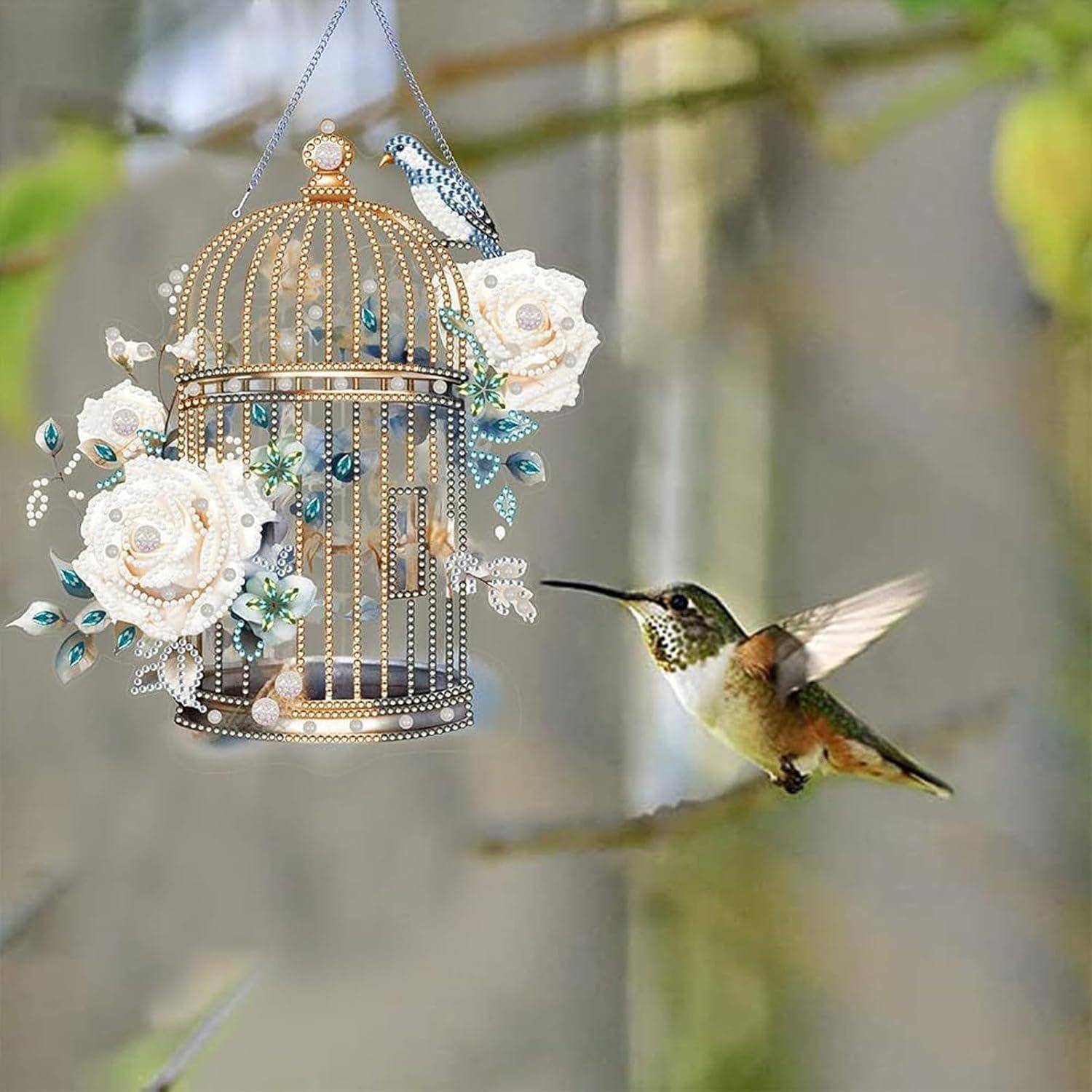 Ein Kolibri schwebt neben einer reich verzierten hängenden Vogelkäfigdekoration mit weißen Blumen und Perlen.