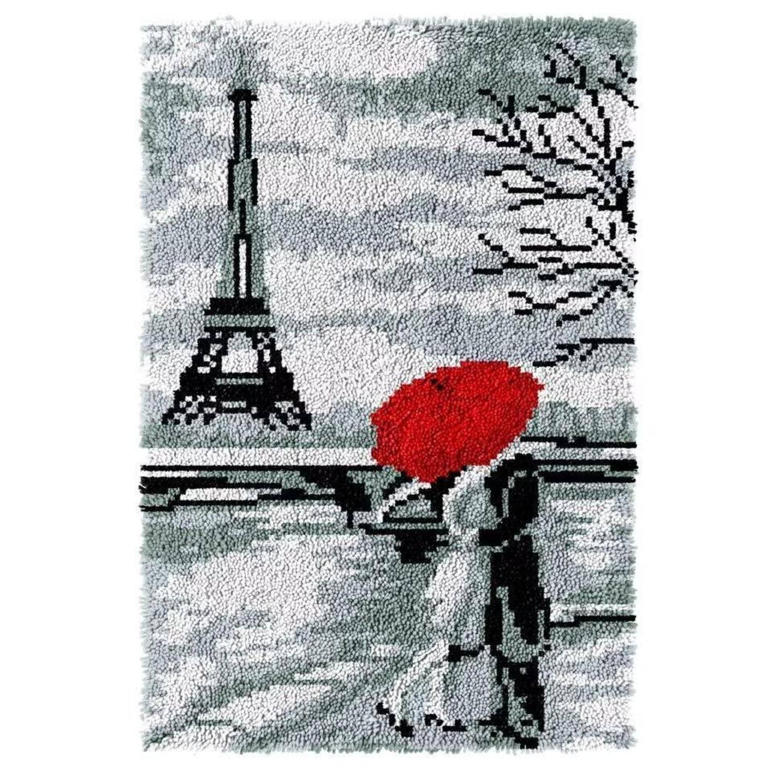 Eine Person hält einen roten Regenschirm und spaziert an der Seine vorbei, während der Eiffelturm im Hintergrund zu sehen ist, an einem verschneiten, grauen Tag.