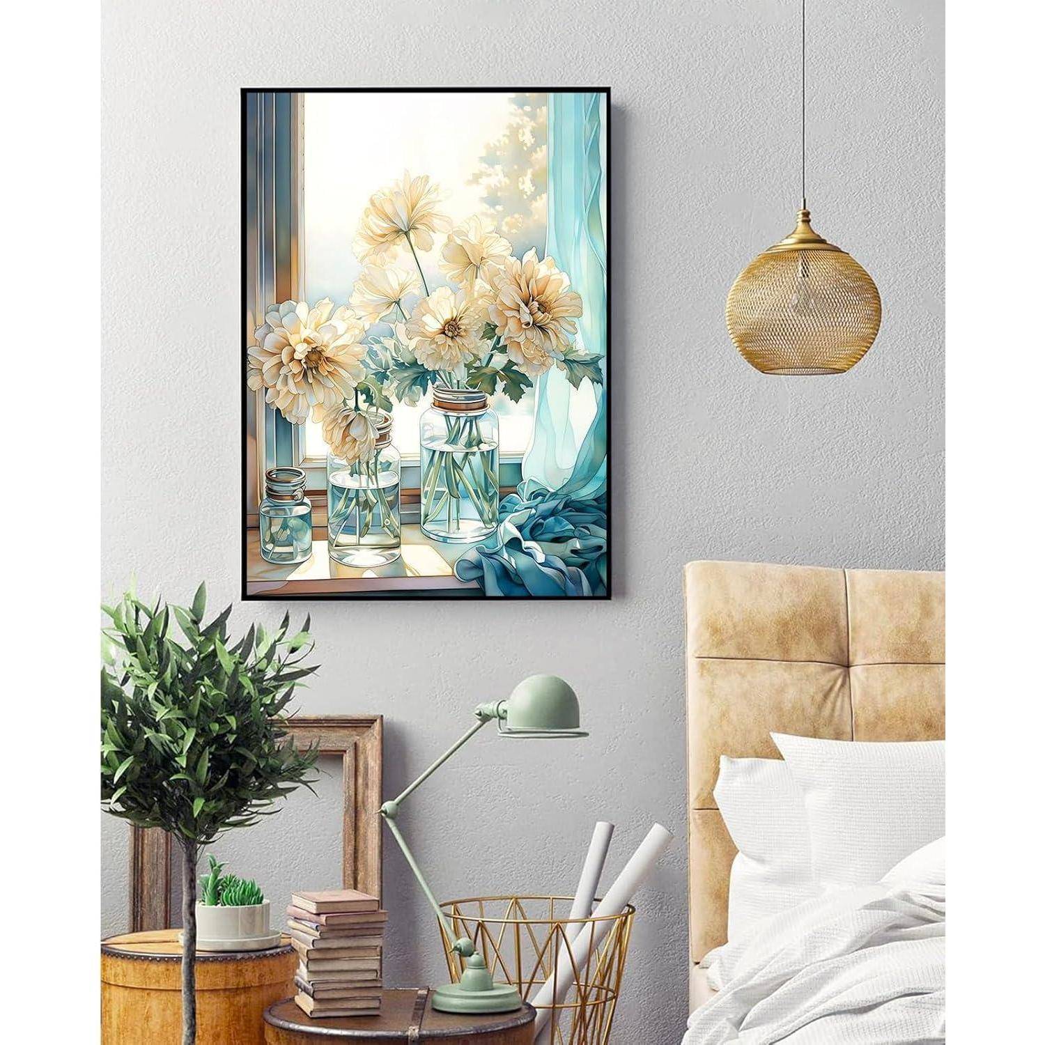 Stilvolle Schlafzimmerecke mit gerahmtem Blumenwandkunstwerk, Pendelleuchte, Nachttischlampe, Pflanze, Büchern und einem Bett mit beigem gepolstertem Kopfteil und weißer Bettwäsche.