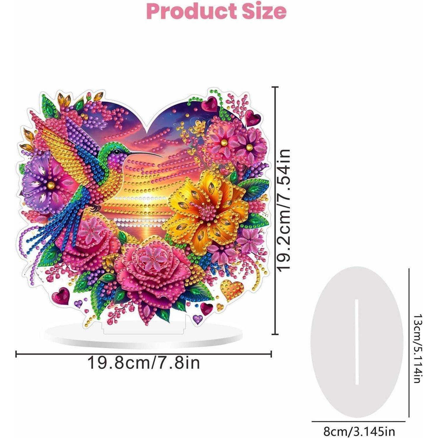 Produktgrößendiagramm, das ein herzförmiges Diamantgemälde mit Kolibri und Blumen zeigt, das 19,8 cm breit und 19,2 cm hoch misst, plus ein ovales Standfuß-Sockel von 13 cm mal 8 cm.