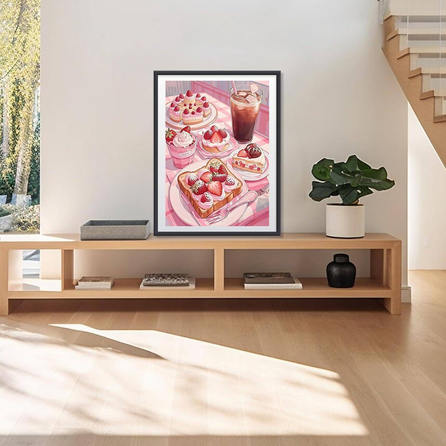 Gerahmte rosafarbene Dessert-Illustration auf einer niedrigen Holzkonsole in einem hellen, minimalistischen Wohnzimmer, neben einer Topfpflanze und einer Treppe.