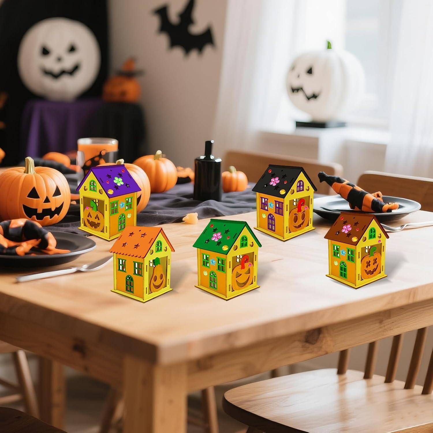 Halloween-Tisch mit kleinen dekorierten Häuschen, Kürbislaternen, Kerzen und schwarz-orangenen Tischdekorationen.