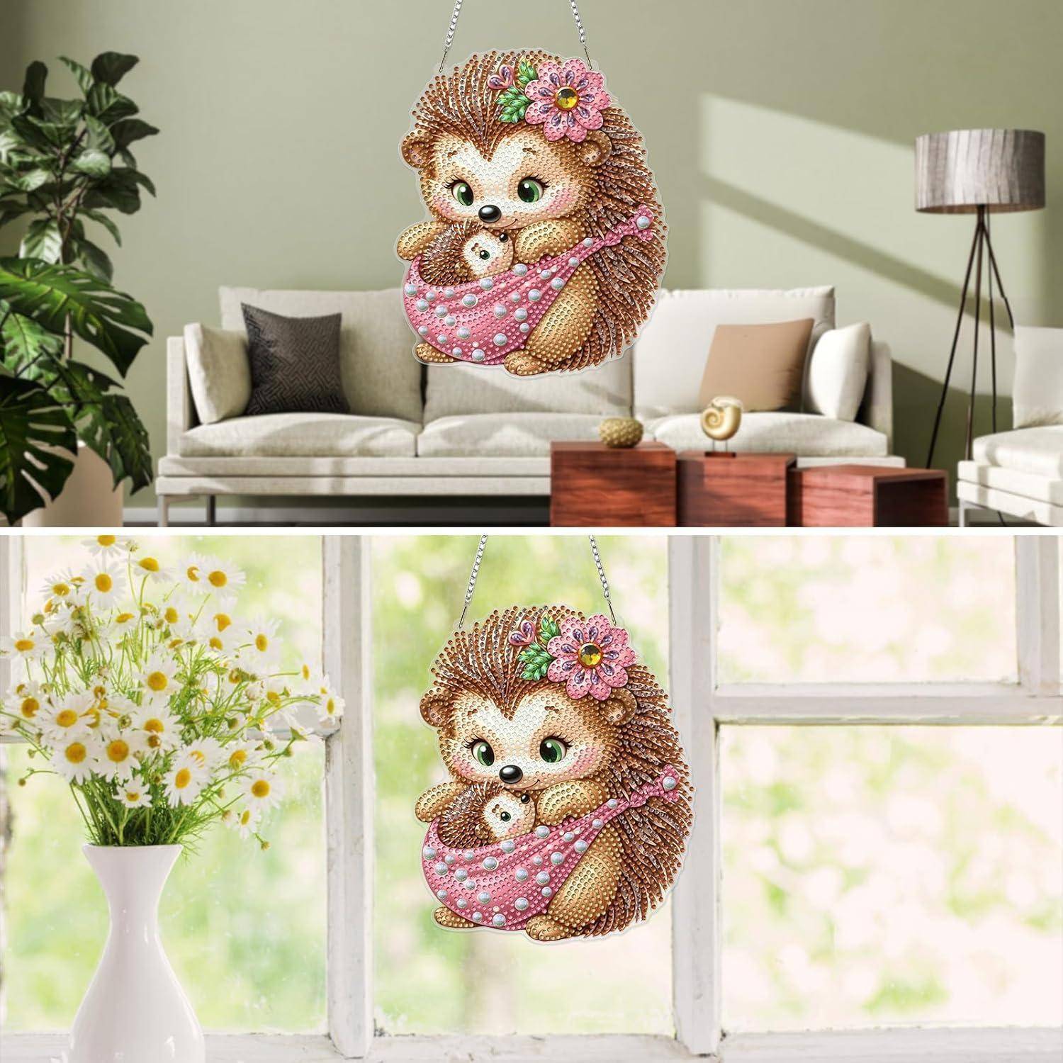 Hängende Igel-Dekoration mit einem Baby in einer rosa Tragetuch, gezeigt in einem Wohnzimmer und an einem Fenster mit Blumen.