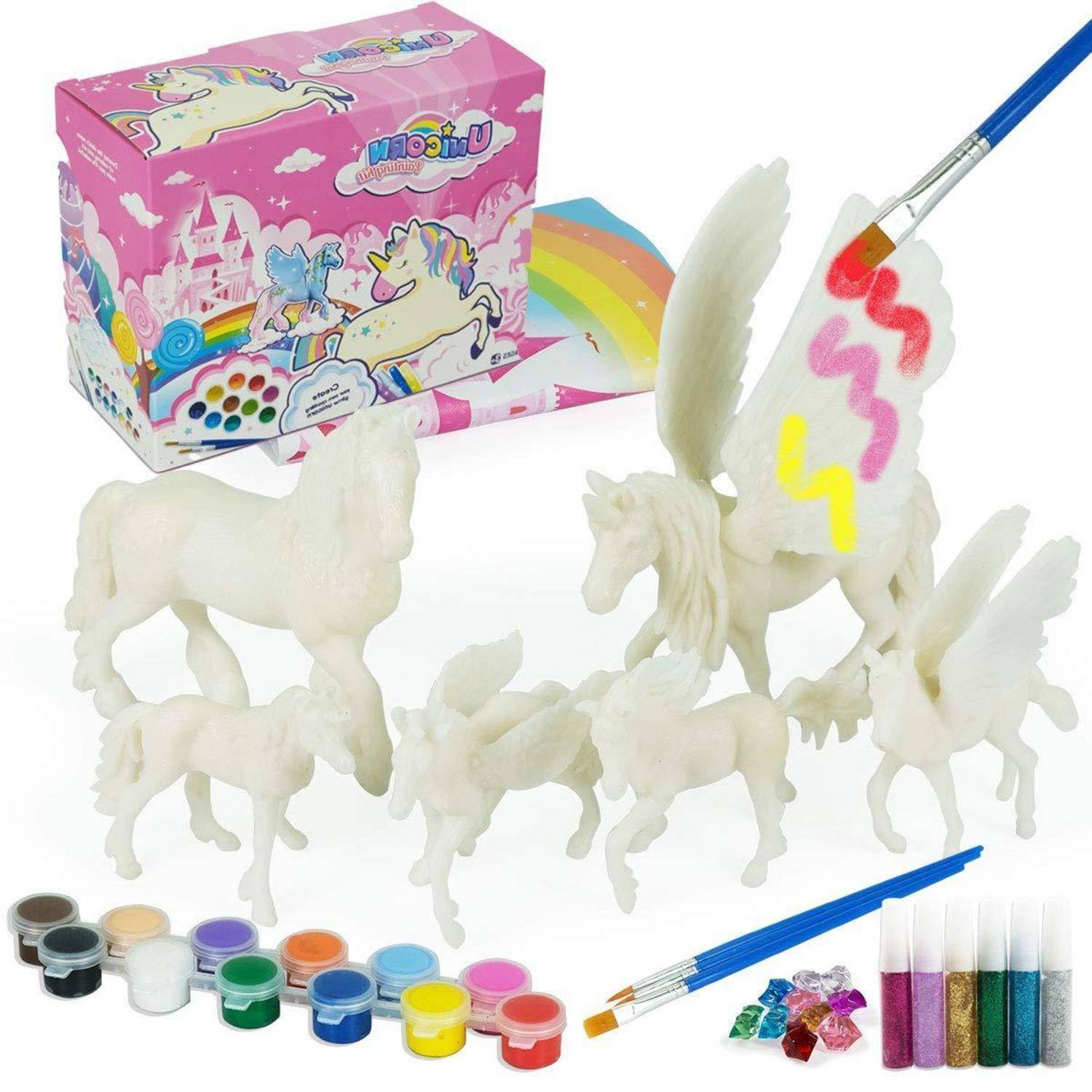 Unbemalte Einhorn-Figürchen und Bastelmaterialien, einschließlich Farbdosen und Pinseln, wobei ein Einhorn in Regenbogenfarben bemalt neben einer dekorativen Produktbox steht.