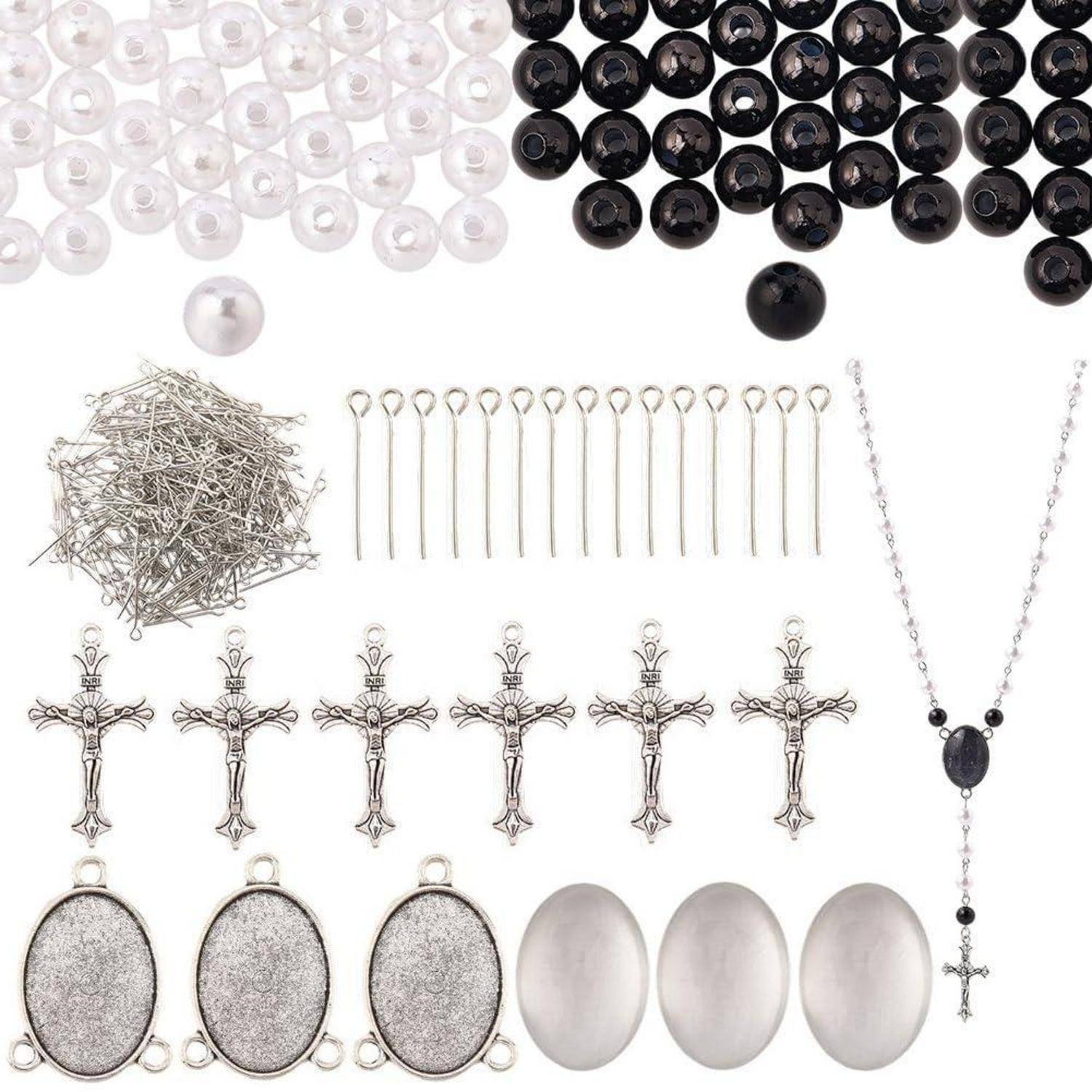 Gemischte Schmuckherstellungsmaterialien: weiße und schwarze Perlen, Ösennadeln, Kopfnadeln, silberne Kreuzketten, ovale Fassungen und eine Kreuzkette mit schwarzen Perlen.