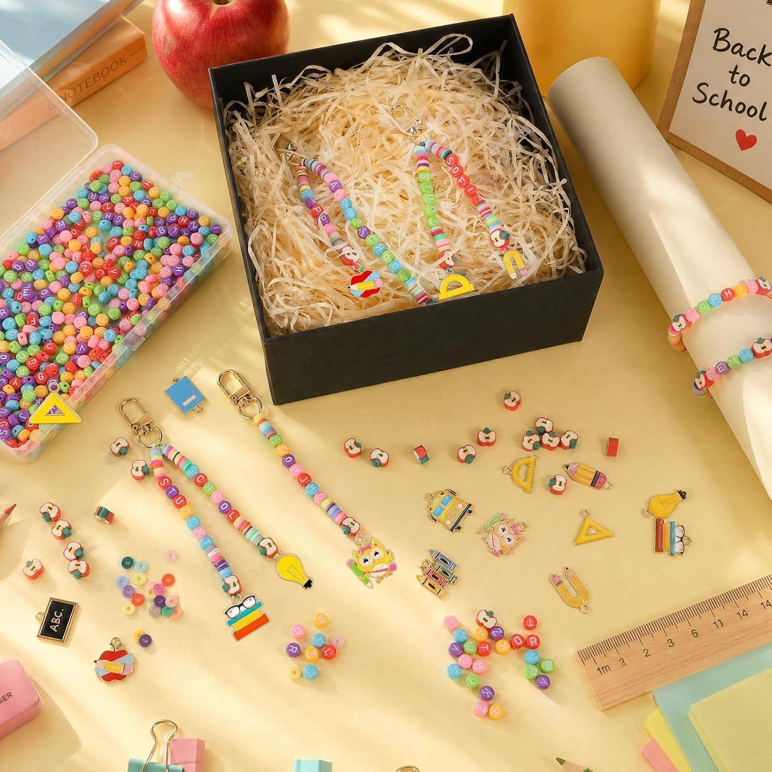 Sortierte bunte schulthematische Perlenaccessoires und Anhänger, die in einer Geschenkbox und auf einem Tisch angeordnet sind, mit einem 