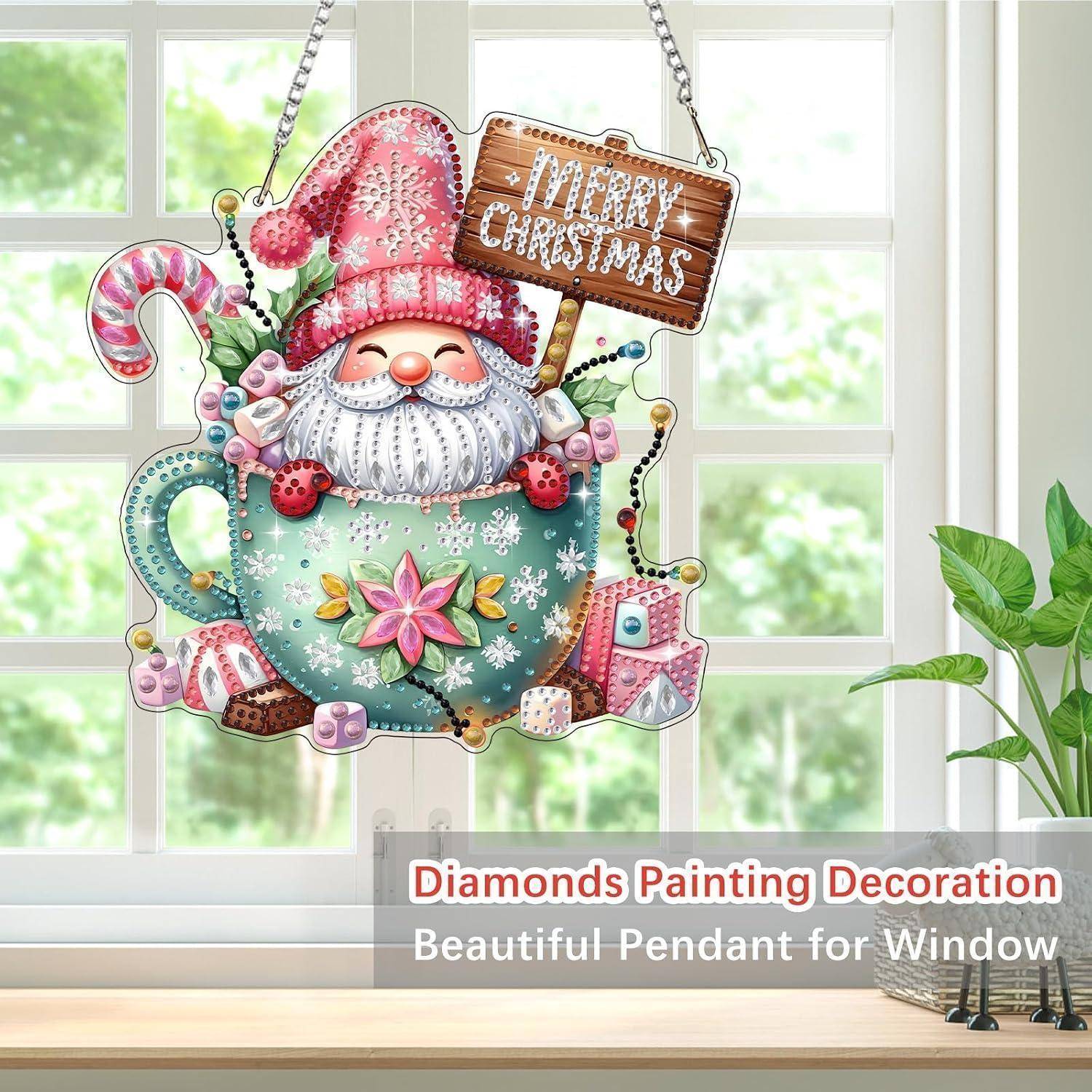 Dekoratives Hängeornament für das Fenster mit einem lächelnden Weihnachtswichtel in einem rosa Hut in einer blaugrünen Teetasse, der ein Schild mit der Aufschrift „FROHE WEIHNACHTEN