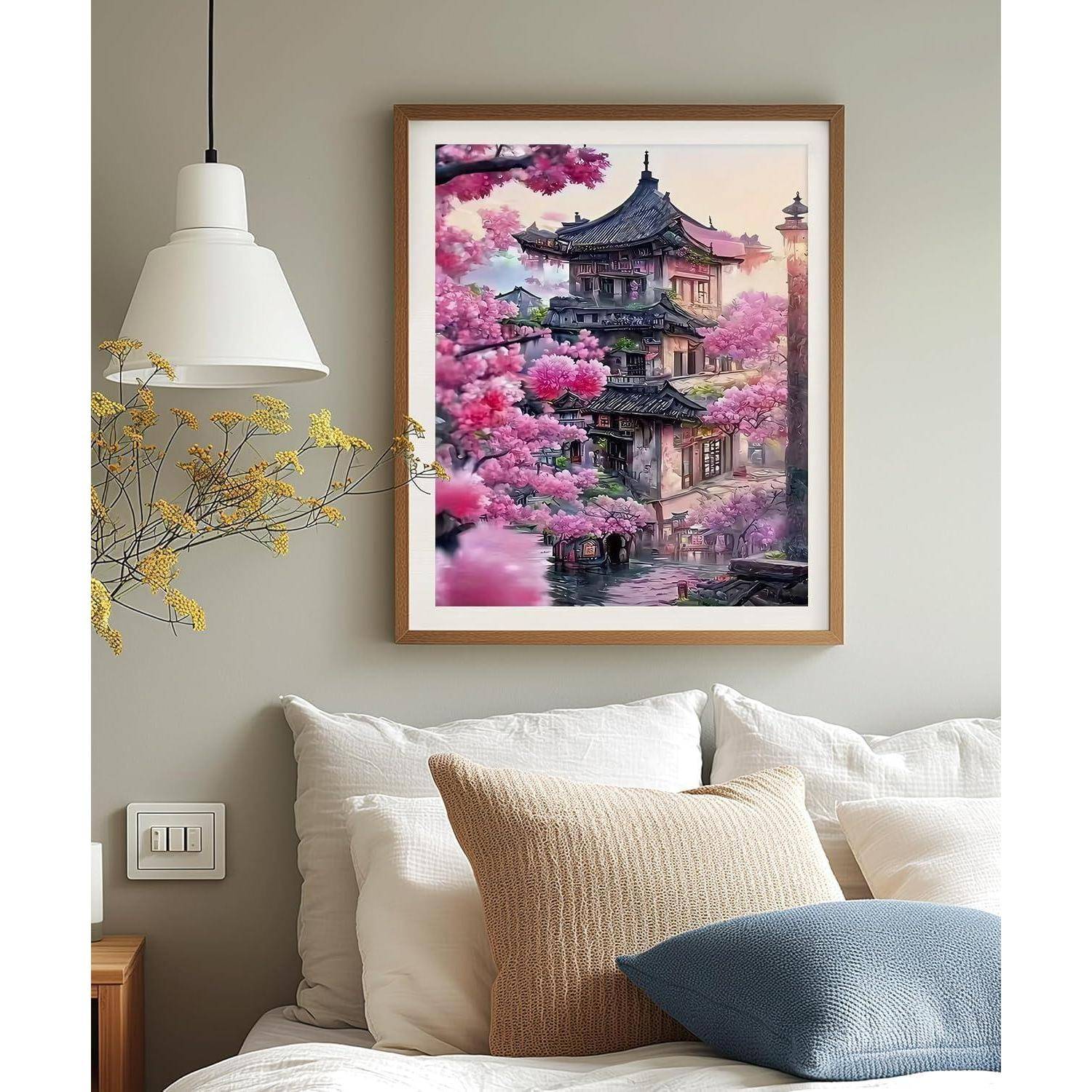 Schlafzimmer-Wandkunst über einem Bett zeigt ein gerahmtes Gemälde eines traditionellen Tempels, umgeben von rosa Blüten.