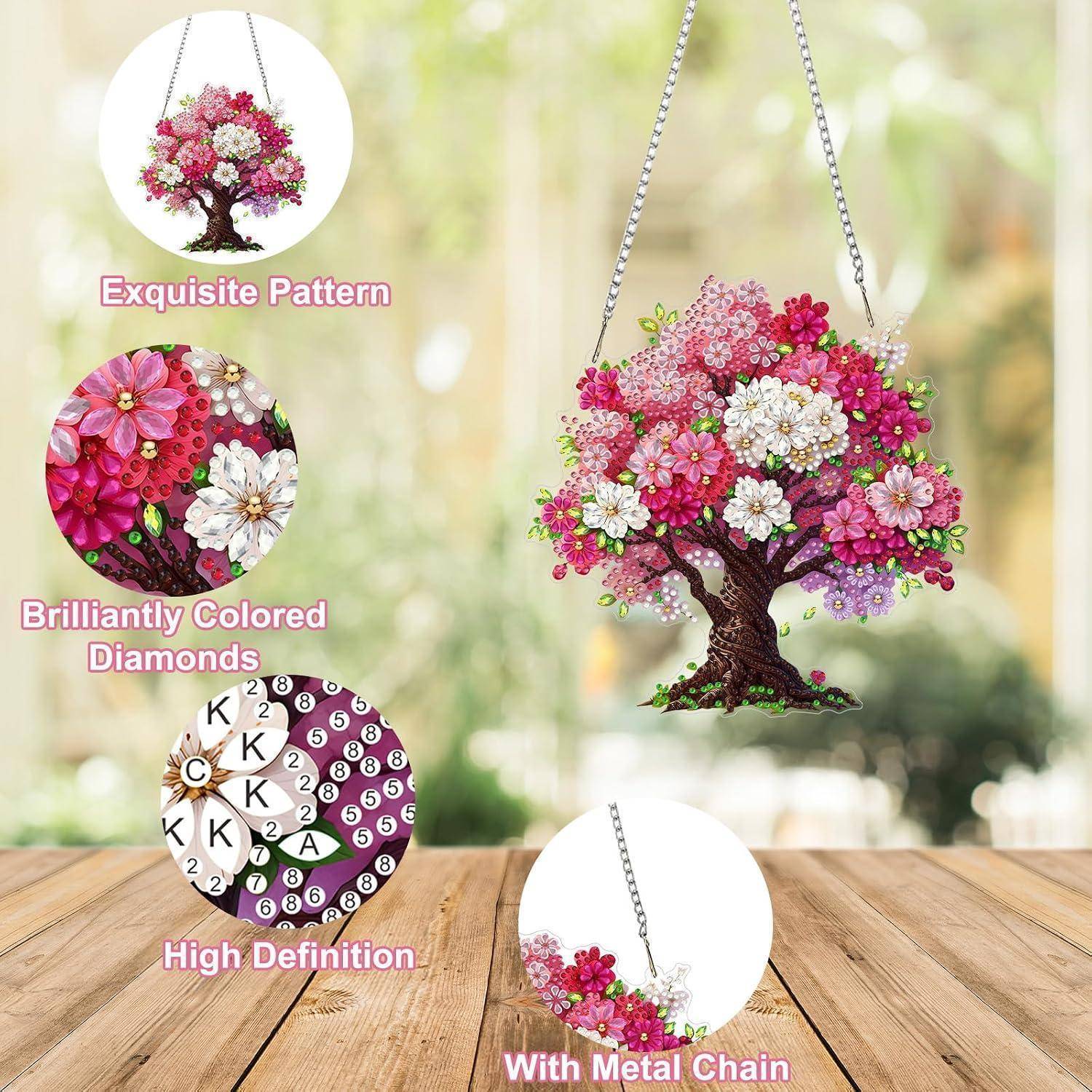 Diamantmalerei eines rosa und weißen Blütenbaumanhängers, gezeigt mit Nahaufnahmedetailkreisen und einer Metallkette auf einer Holzoberfläche.