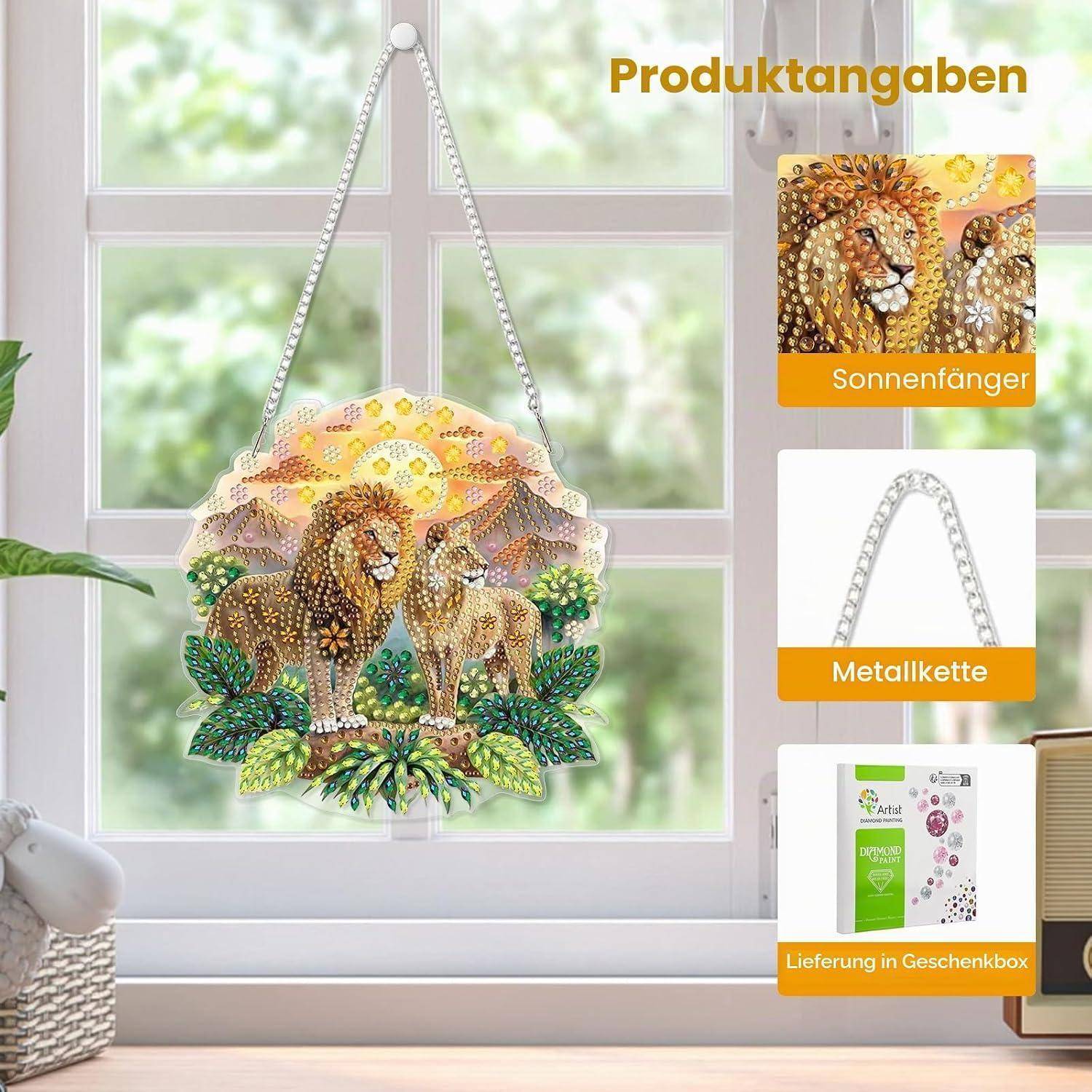 Produktbild eines Löwen und einer Löwin Sonnenfängers, der an einer Metallkette in einem Fenster hängt; eingefügte Etiketten zeigen „Sonnenfänger